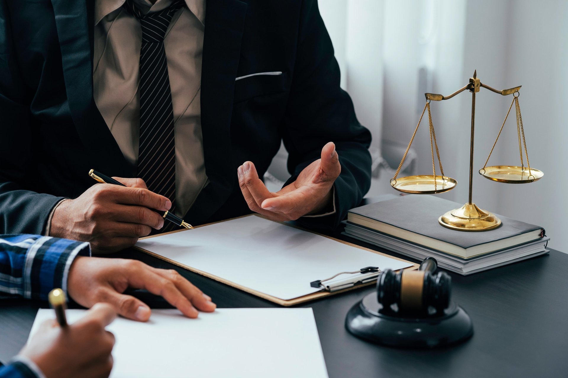 Professional lawyer in a suit providing legal advice with scales of justice and a gavel on the desk.
