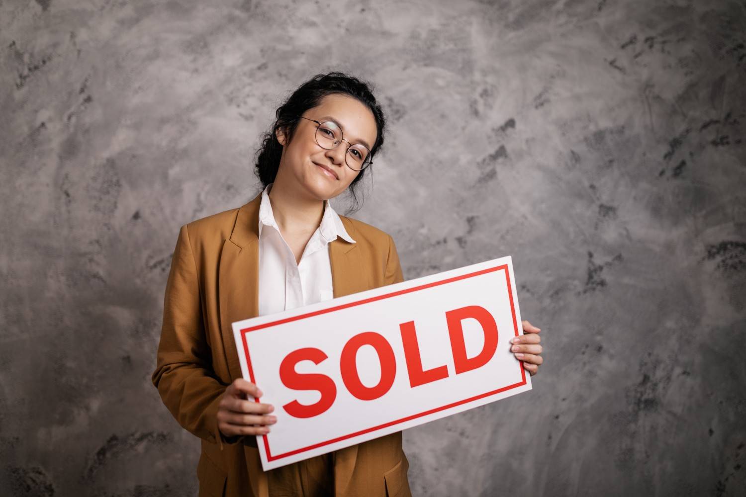 Realtor holding a sold sign in front of a home in a Chattanooga Tennessee neighborhood with Lookout Mountain