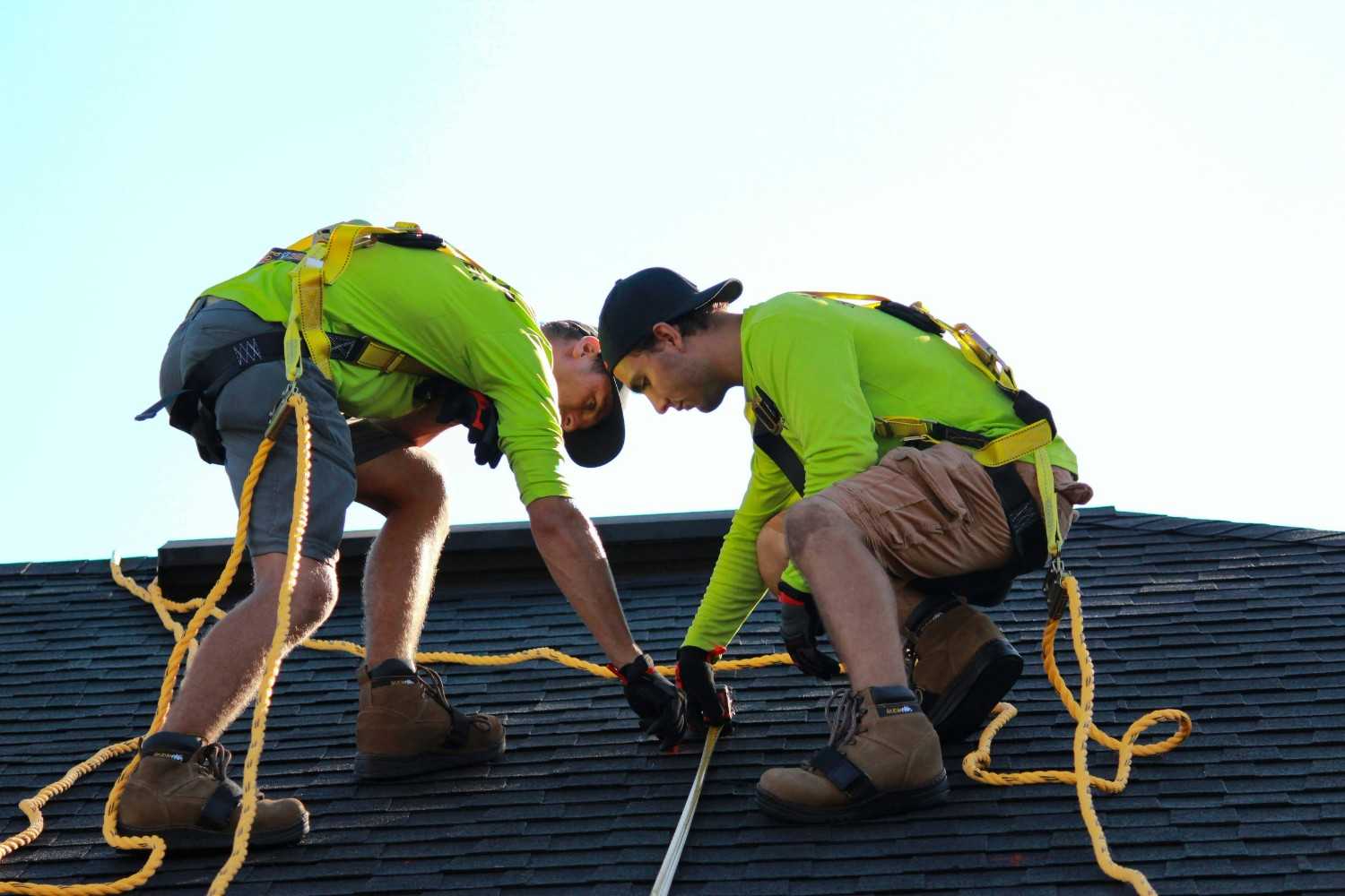 Roofing contractors replacing shingles on a Colorado Springs home with mountain views in the background