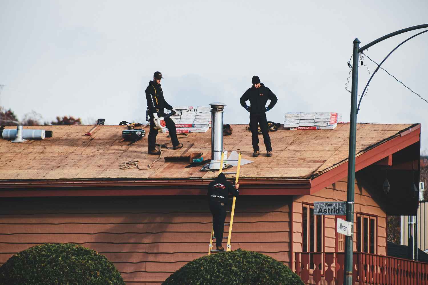 Roofing crew installing shingles on a residential home in Boise Idaho with foothills in the background