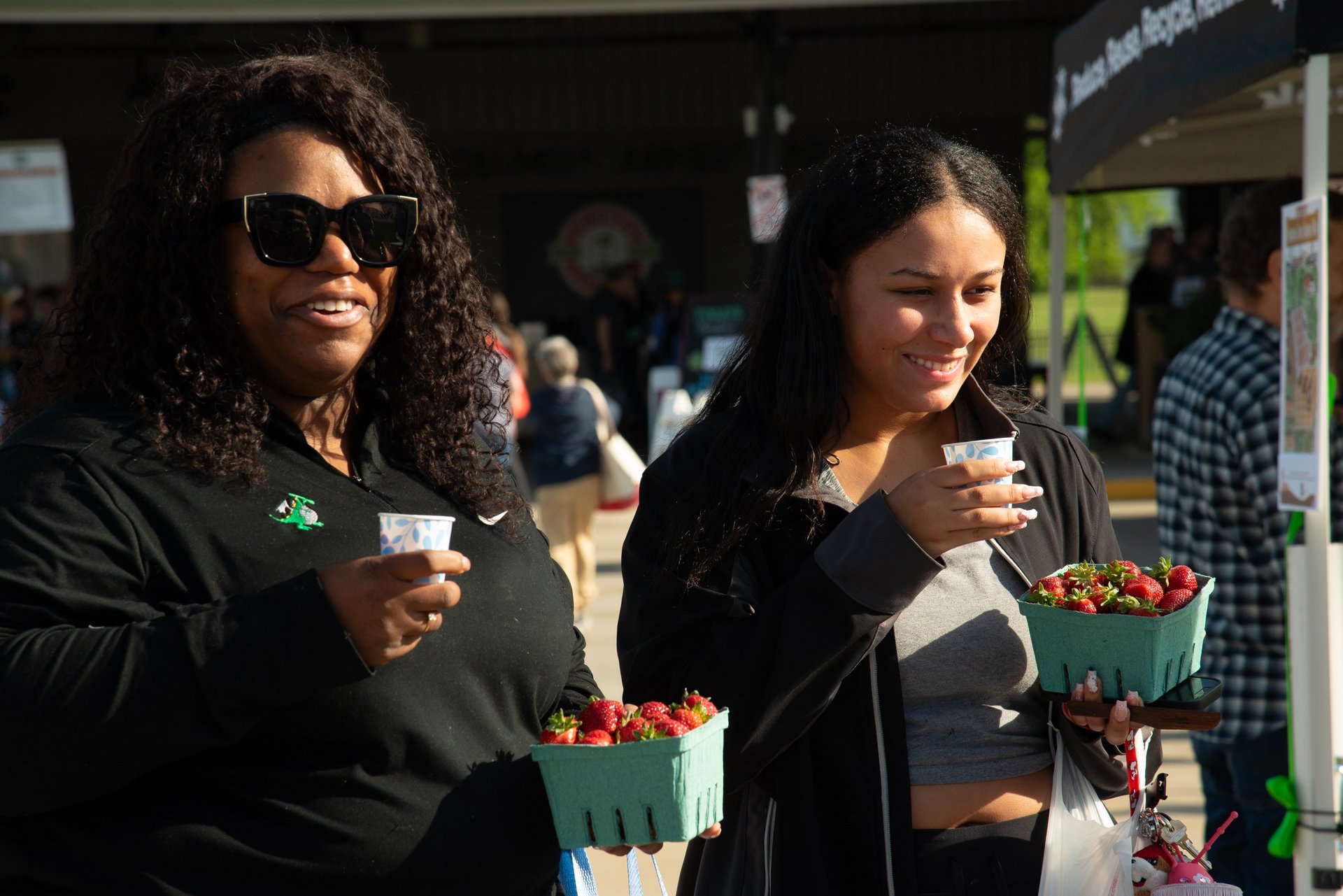 Two adults leaving the farmers market enjoying our bike-powered smoothies