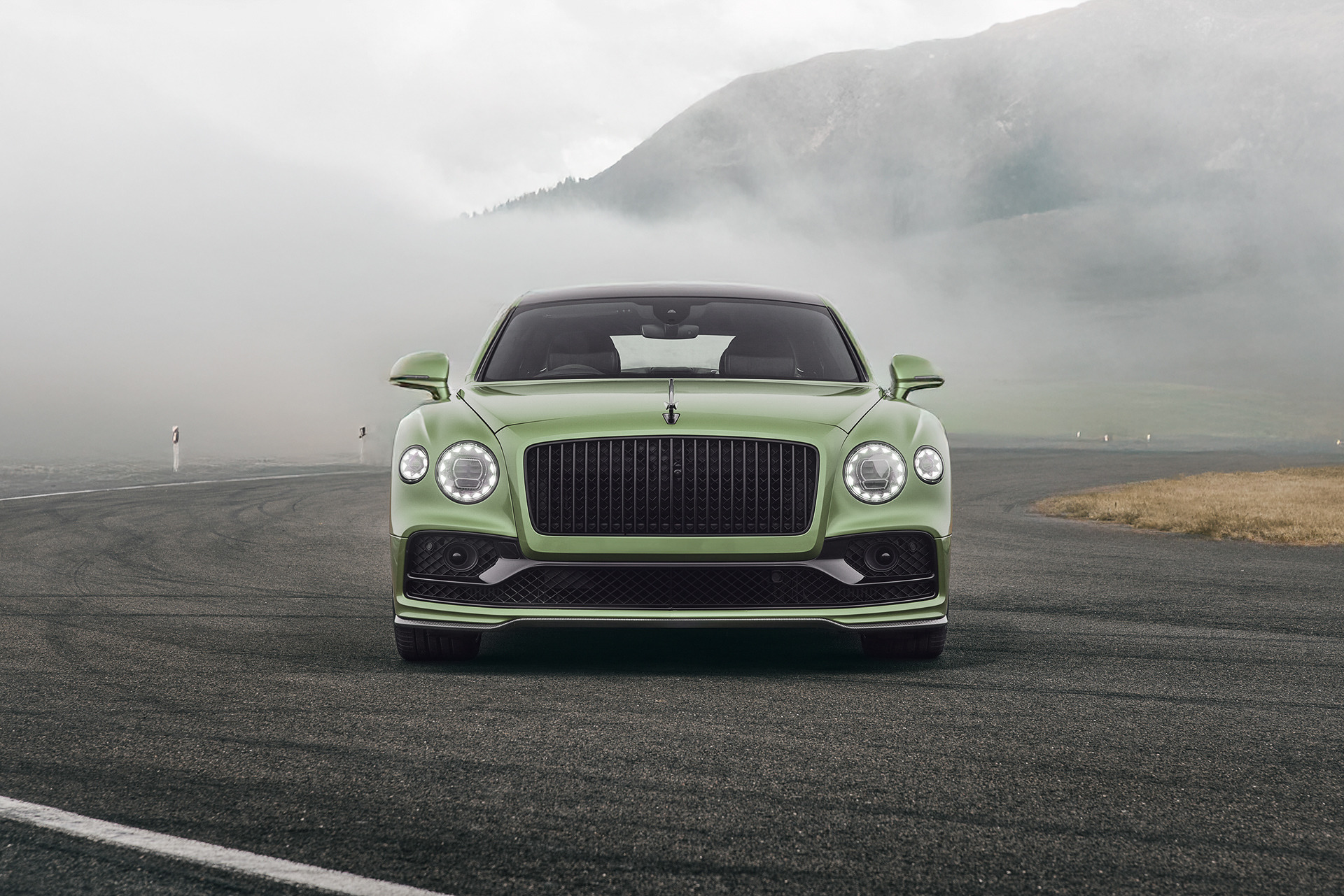 a green bentley flying spur in the swiss mountains