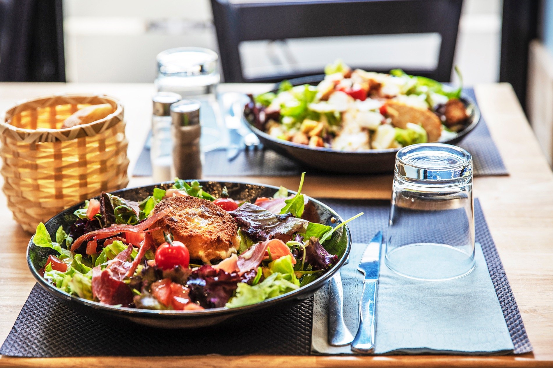 a table with a bowl of salads and a glass of water