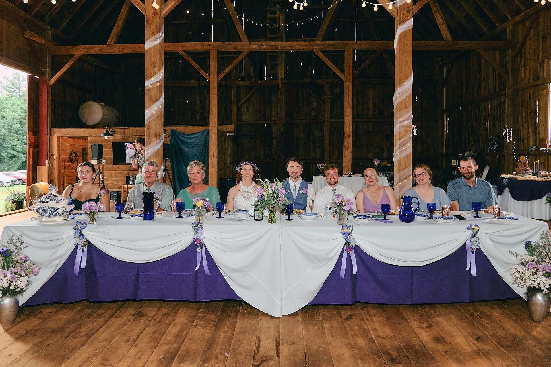 a group of people sitting at a head table with flowers in a wedding reception