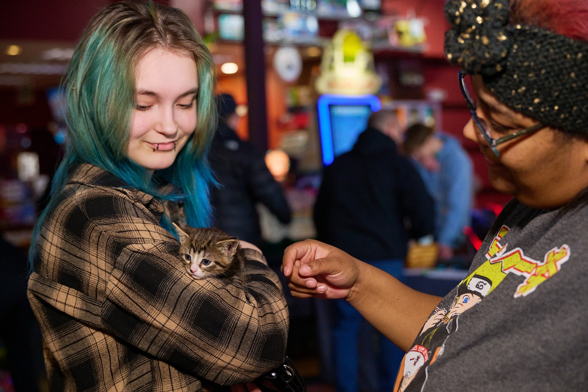 a woman with blue hair holding a kitten on her arm