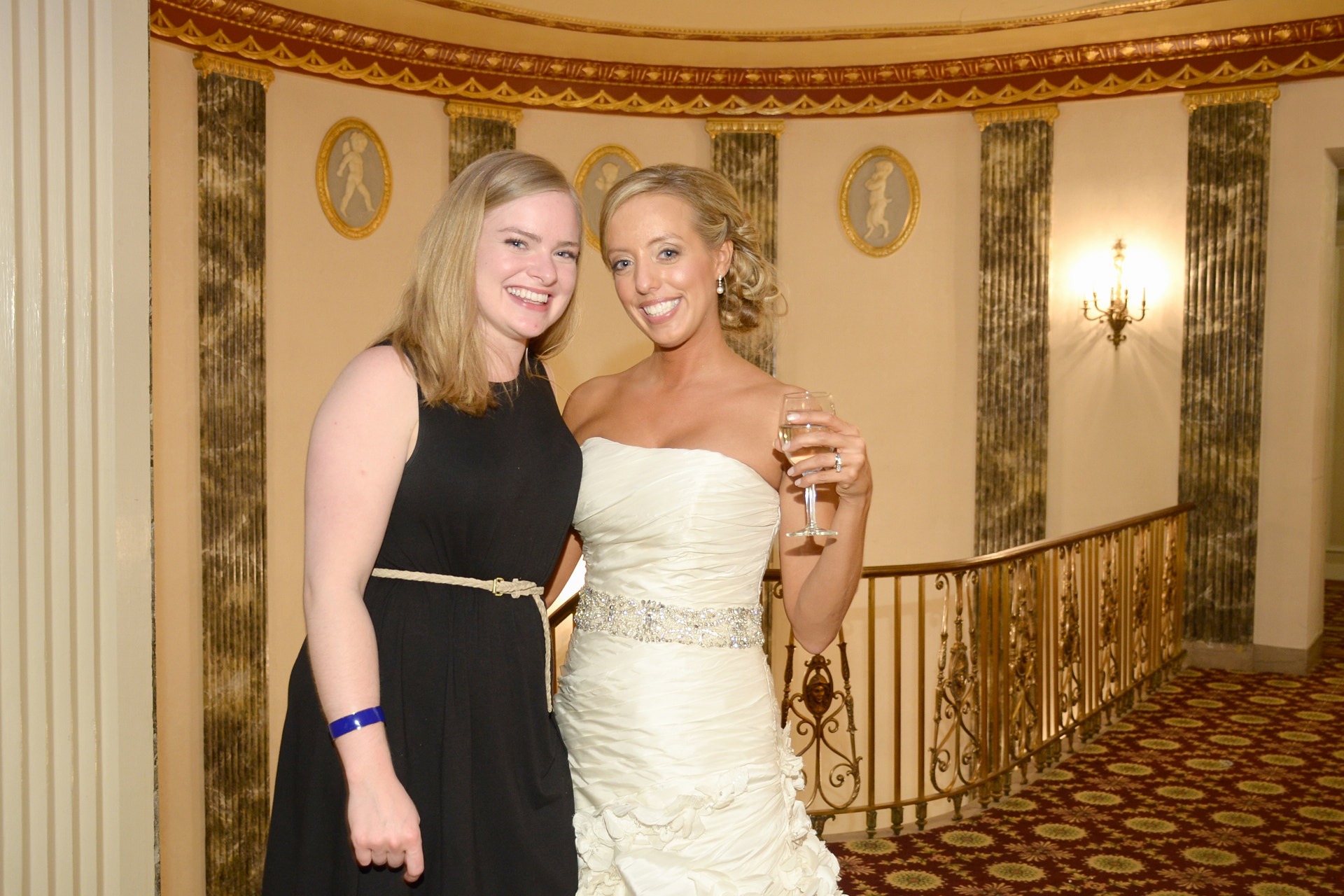 a bride and a female guest in formal wear standing in a hotel lobby