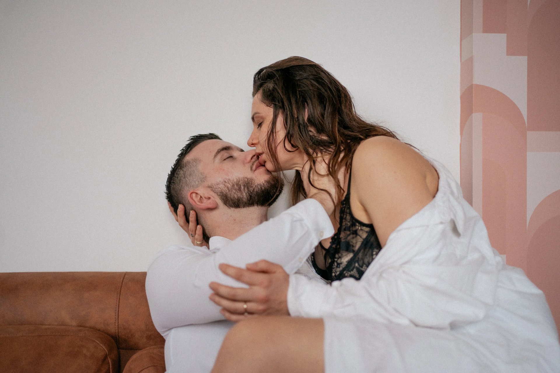 Couple s’embrassant sur un canapé en cuir lors d’une séance photo de couple intimiste à Rennes.