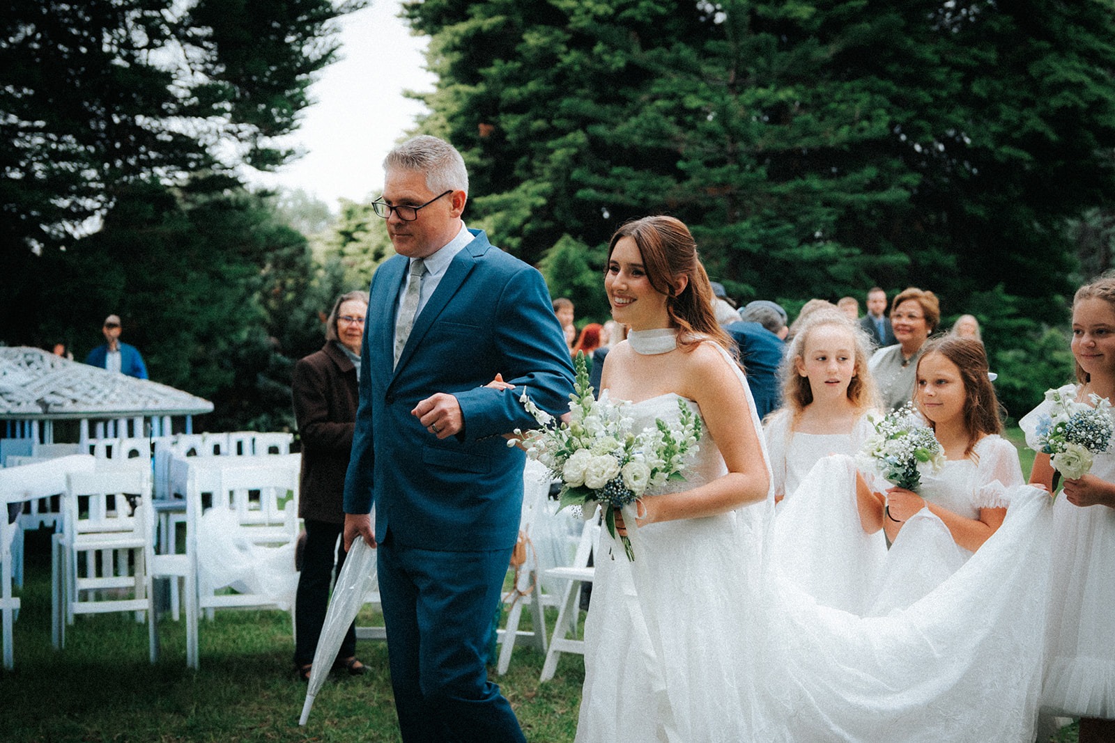 Bride arriving at the ceremony beneath the pine trees at Adelaide Botanic Garden