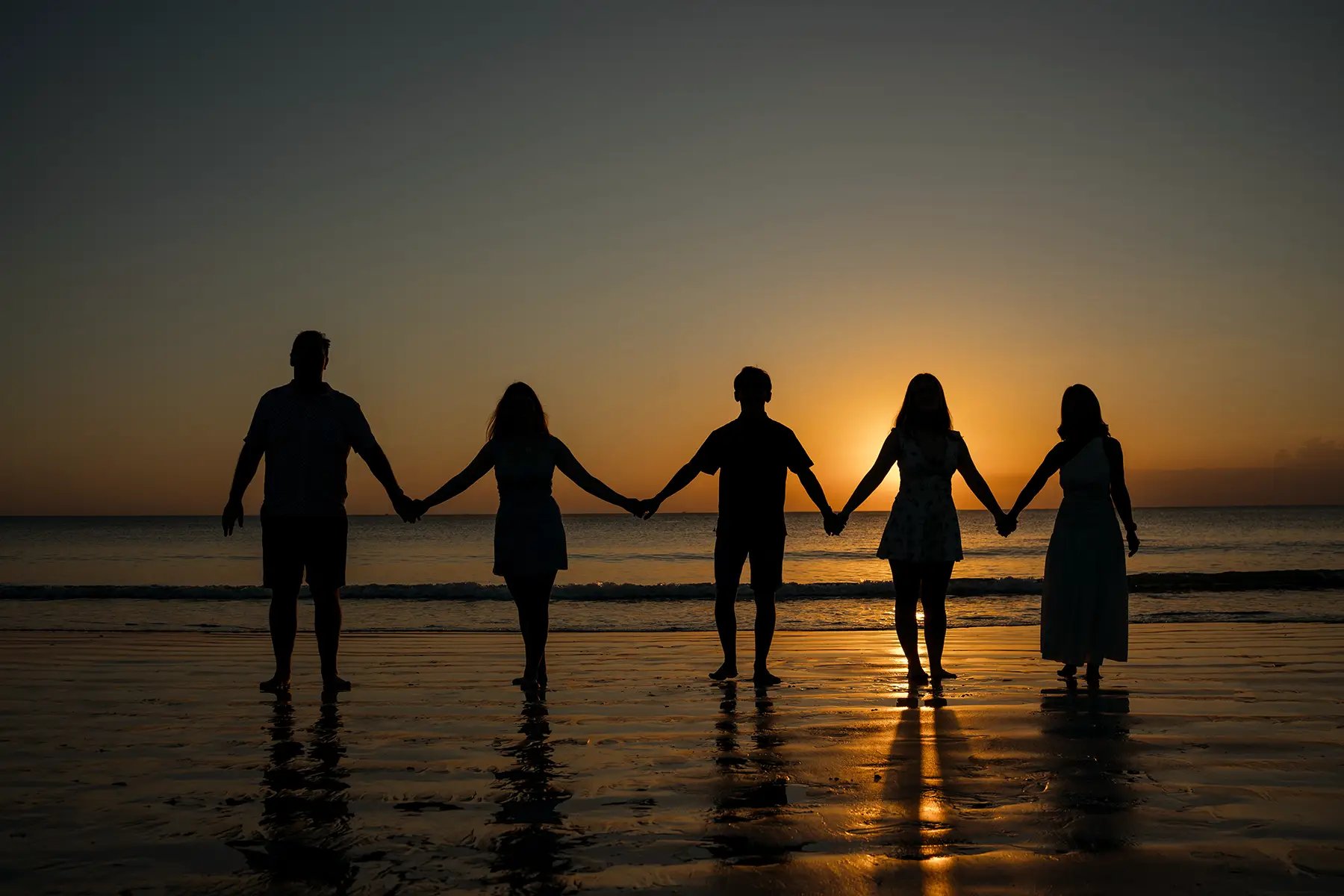 Family silhouette holding hands during sunset at Jimbaran Beach Bali