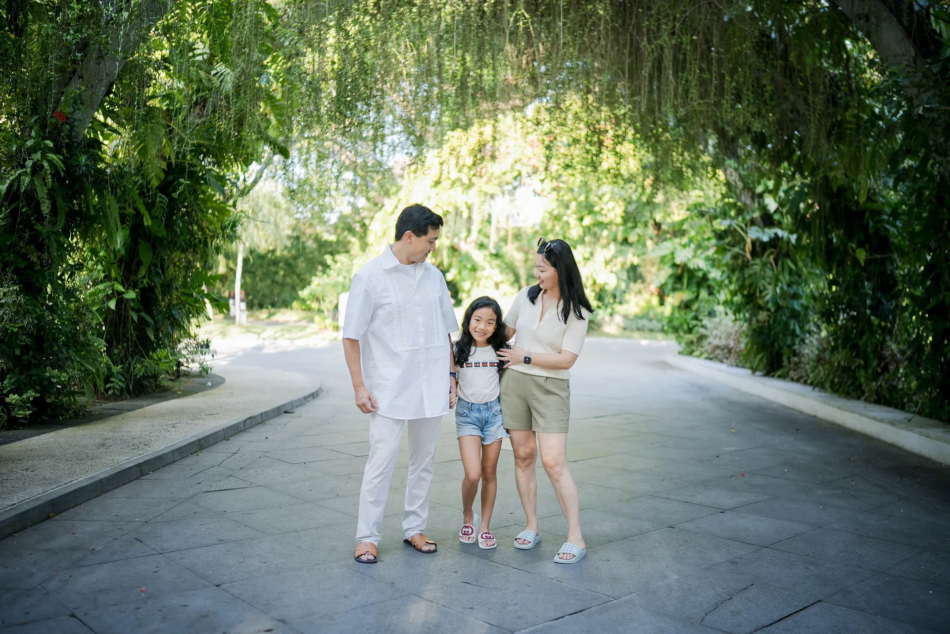 Family strolling through a tropical garden pathway during a family photography session at InterContinental Bali Resort