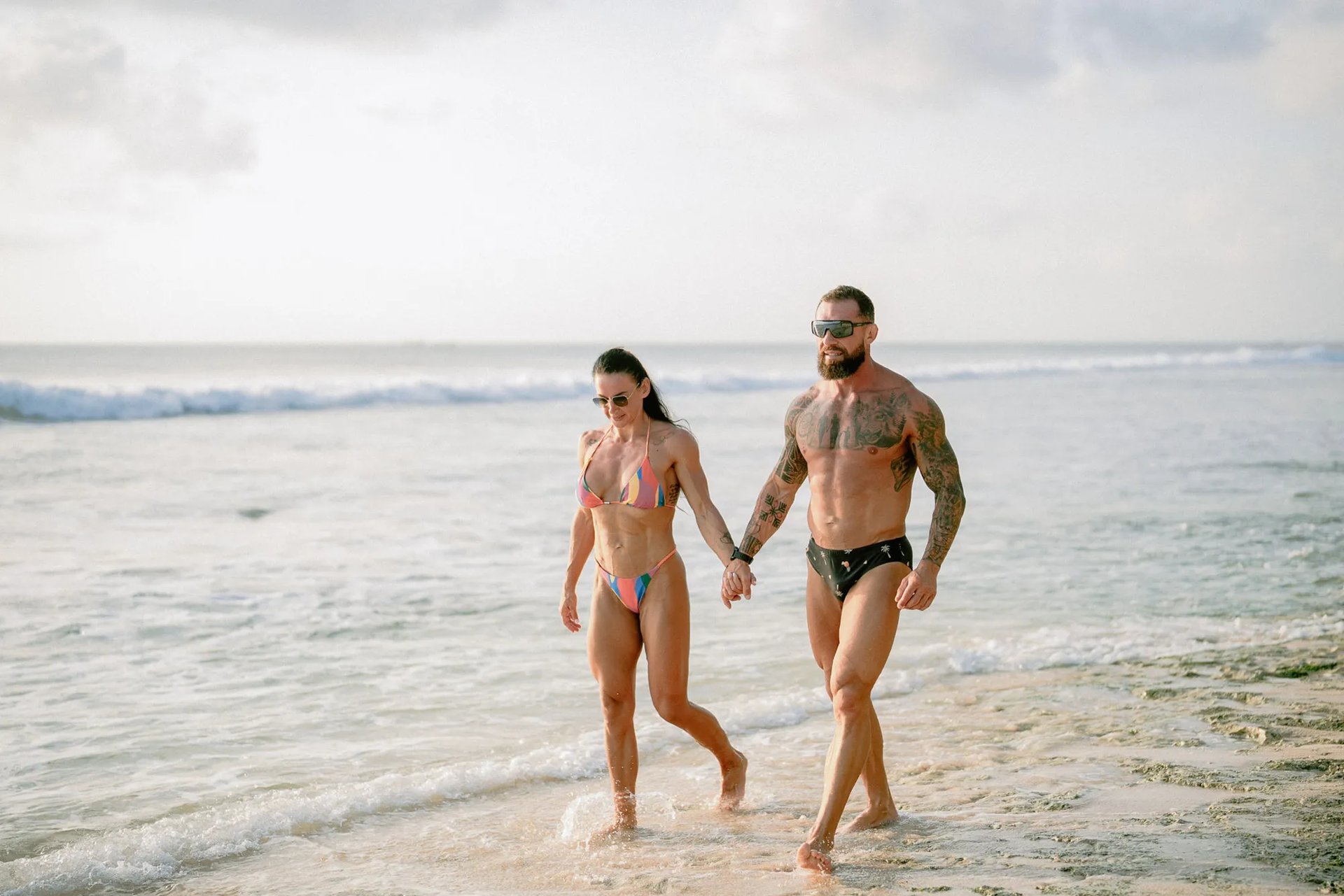 Parents walking together along the shoreline during a relaxed family photography session at Dreamland Beach Bali.