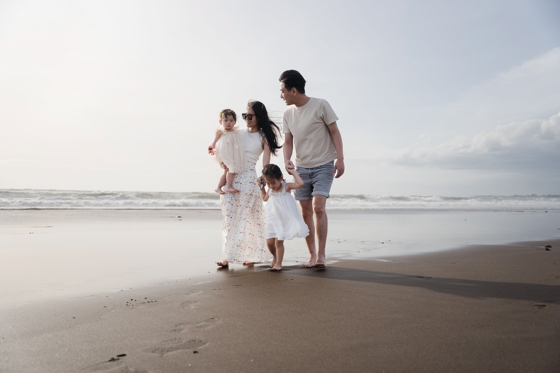 Family enjoying a relaxed walk along Petitenget Beach Seminyak Bali during a natural family photo session