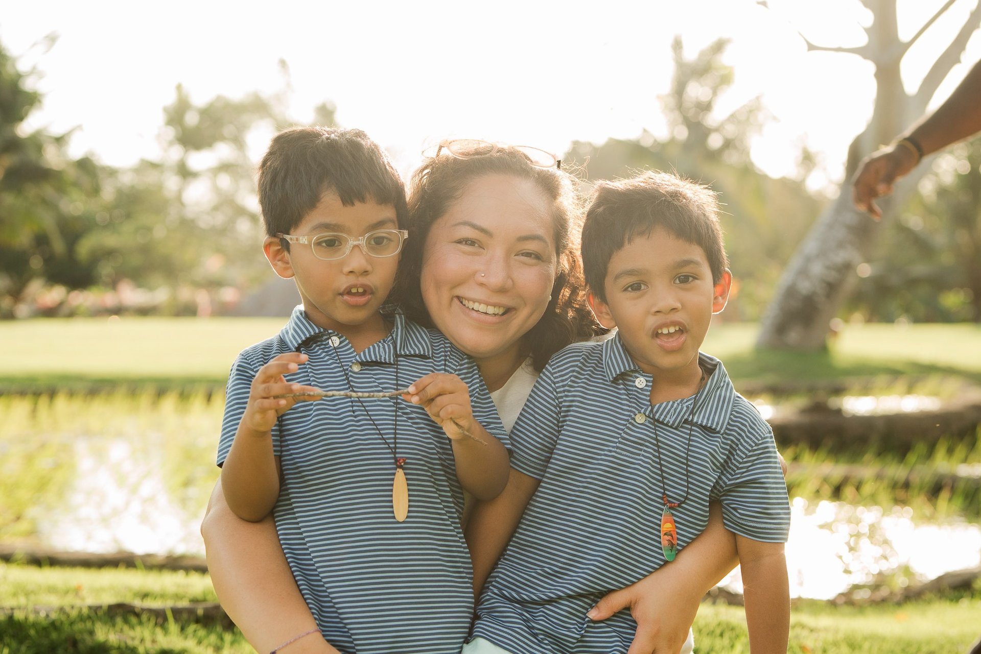 mother hugging her two children in warm sunset light at rimba by ayana bali during a candid bali family photography session