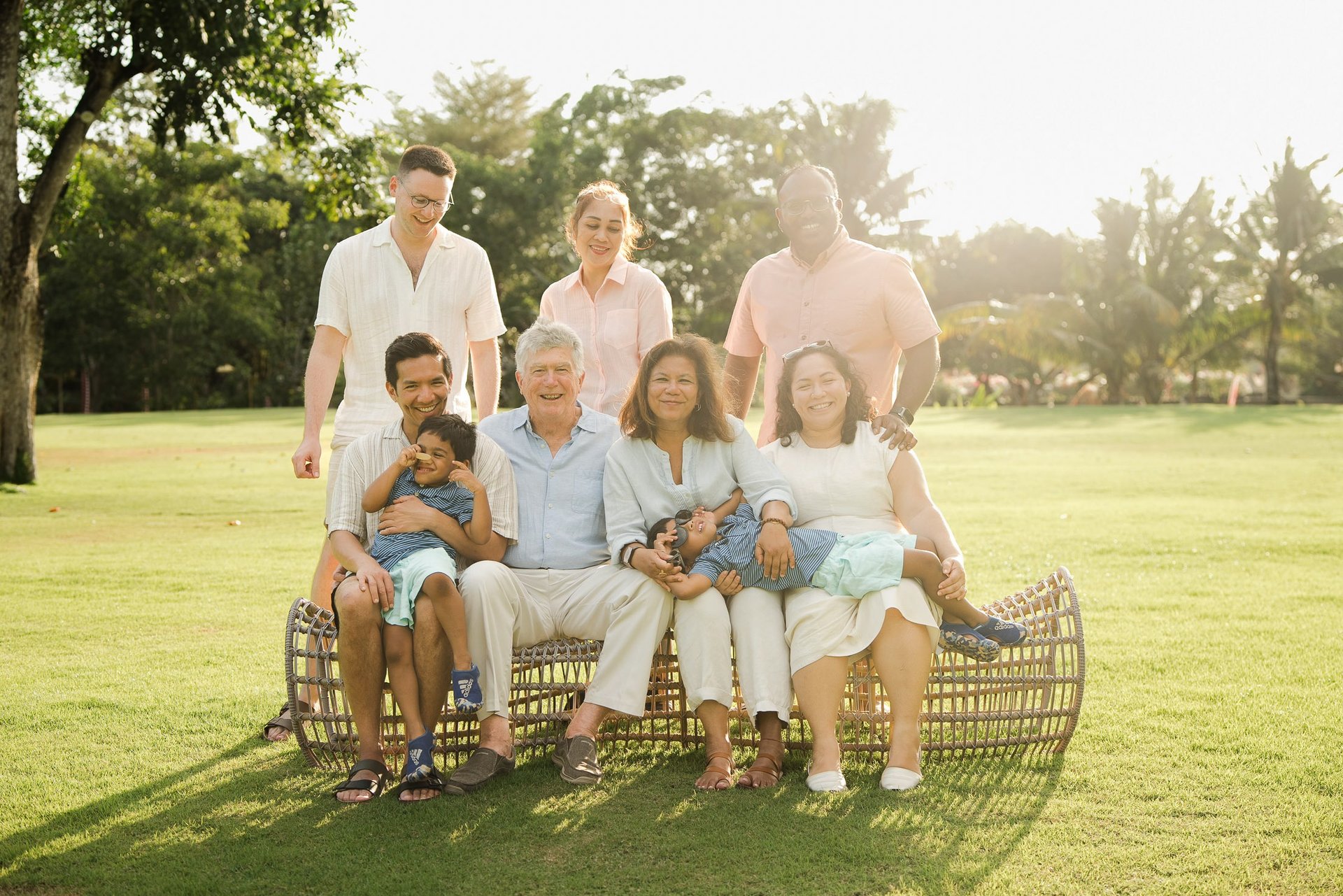 three generation family sitting together on rattan lounge chairs at rimba by ayana bali during sunset bali family photography