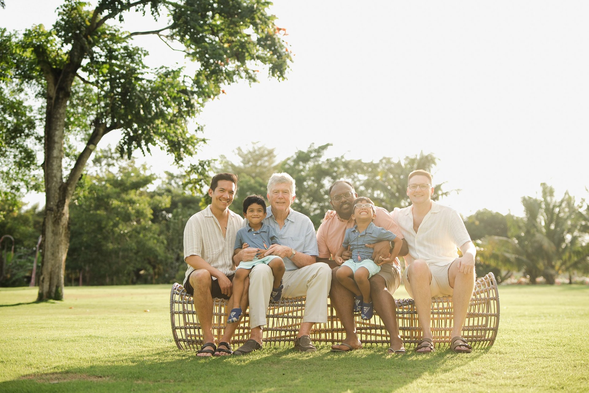 three generation family sitting together on rattan lounge chairs at rimba by ayana bali during sunset bali family photography