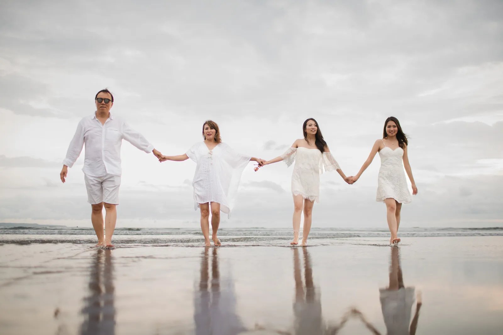 Janice family holding hands on the beach during a family photography session at Indigo Seminyak Bali