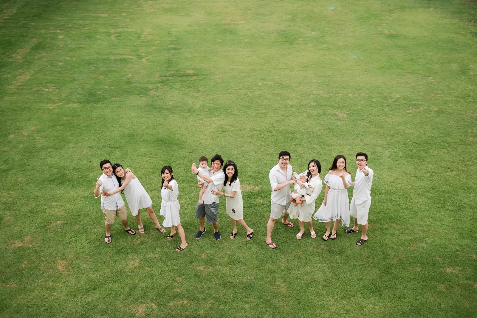 Multigeneration family photography session at Alila Seminyak Bali with family members walking together on green lawn.