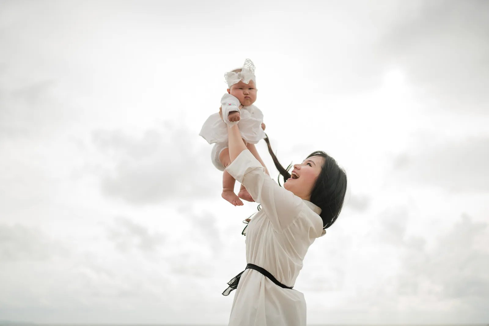Mother lifting baby at Seminyak Beach Bali during soft and emotional family photography moment.