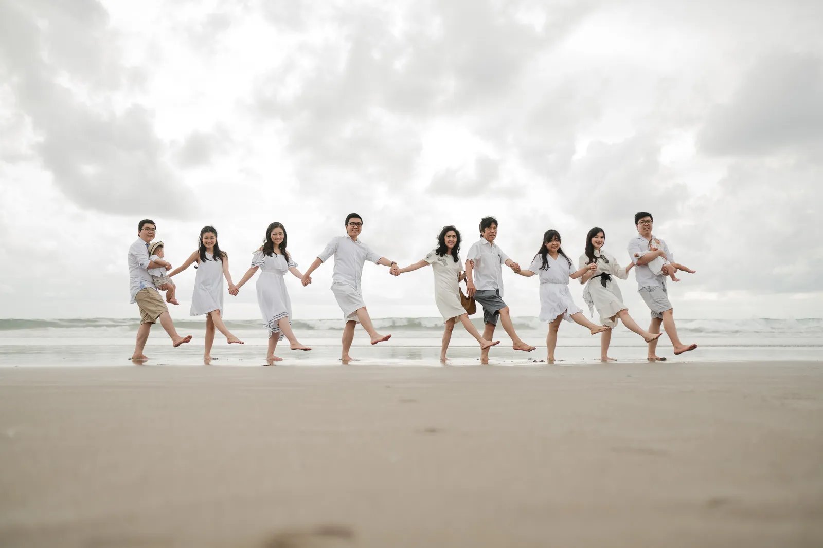 Multigeneration family running together at Bali beach during joyful and candid family photography session.