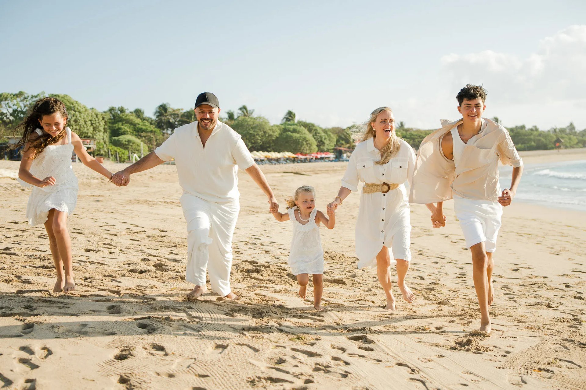 Family running together on the beach during golden hour at Ayodya Resort Bali in Nusa Dua