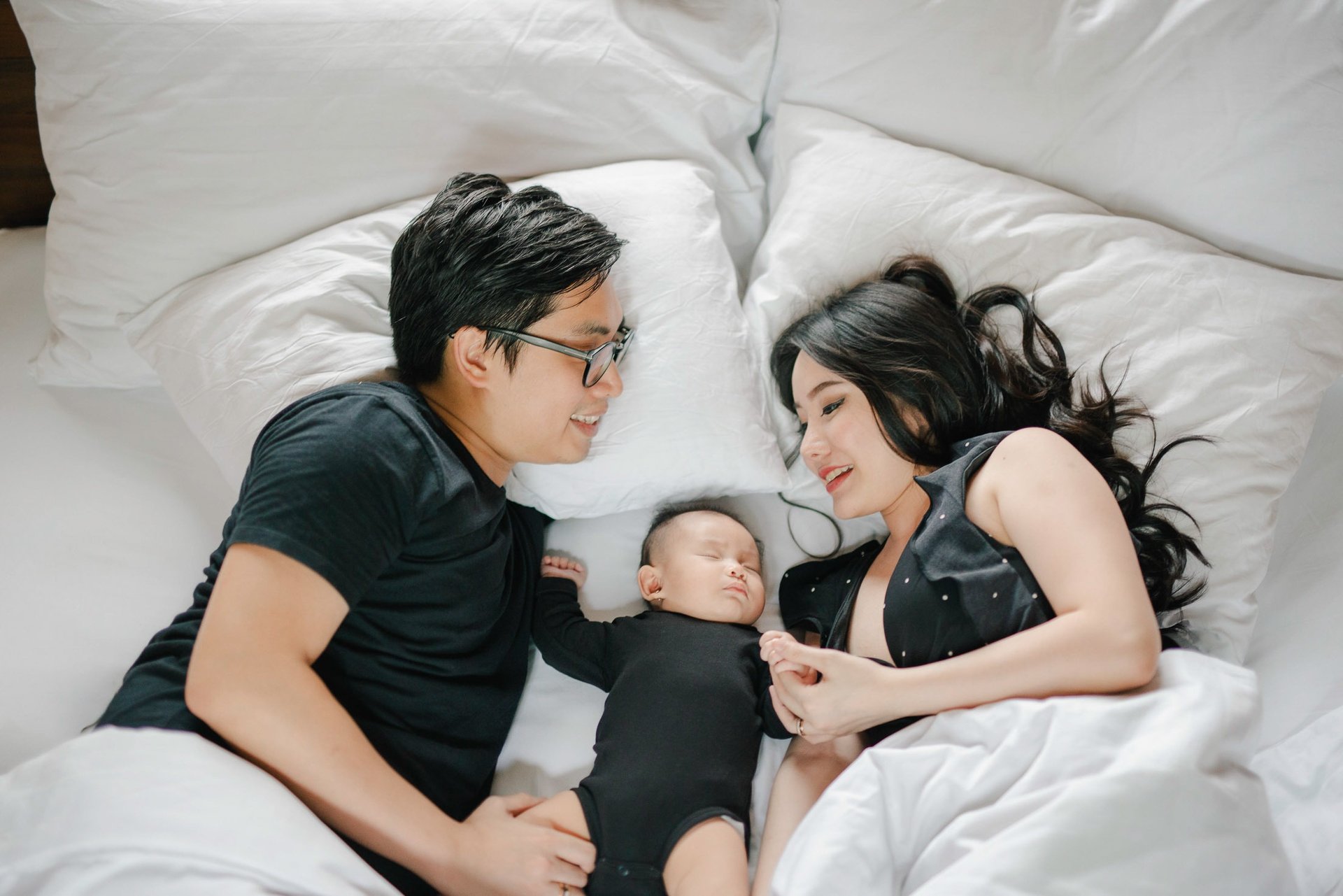Family lying on bed with baby during a family photography session at a private villa in Ubud Bali.