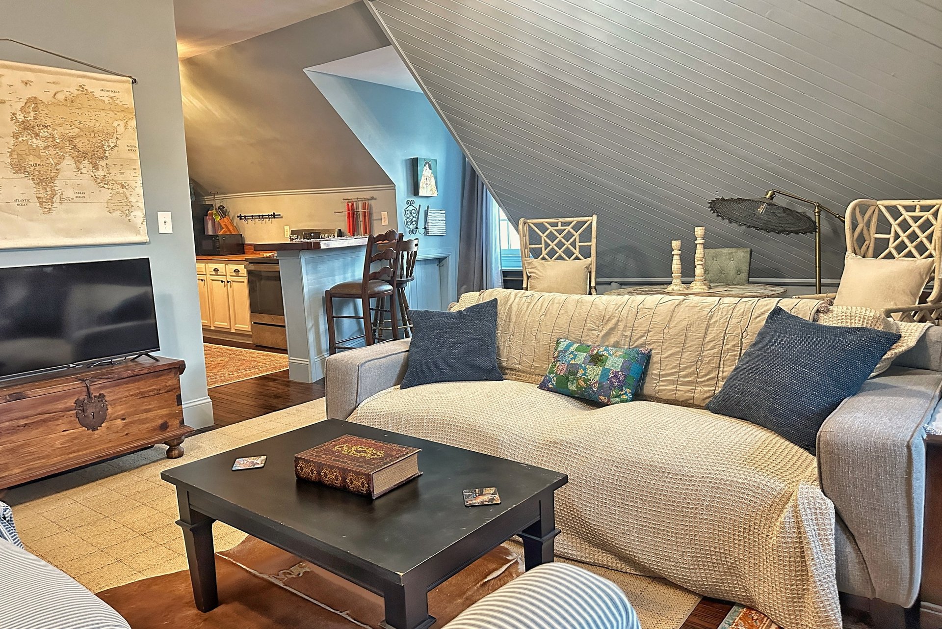 Cozy attic apartment living room with sloped ceilings, comfortable sofa, and vintage world map decor.