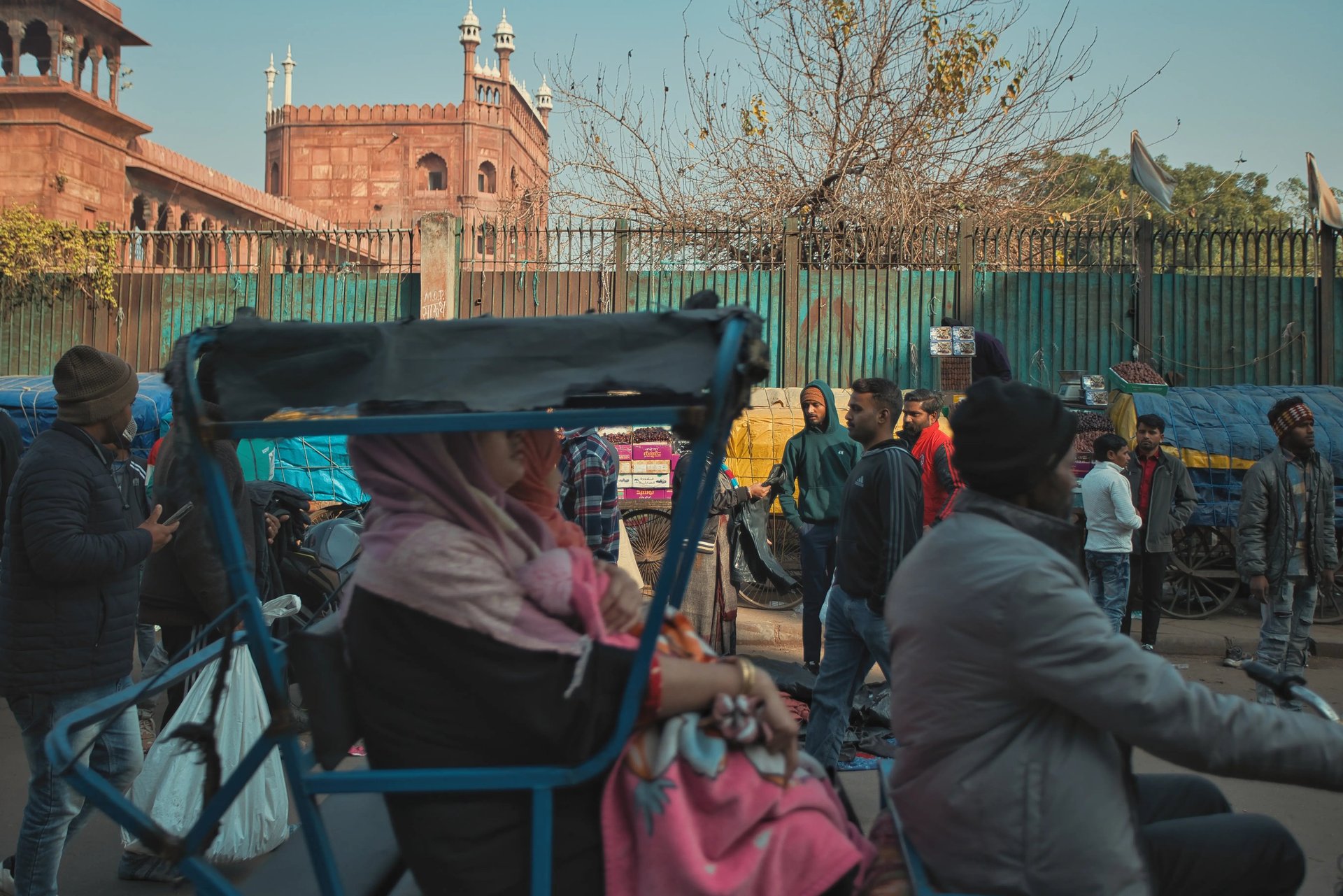 Crowded Old Delhi street with rickshaws and pedestrians near Jama Masjid.