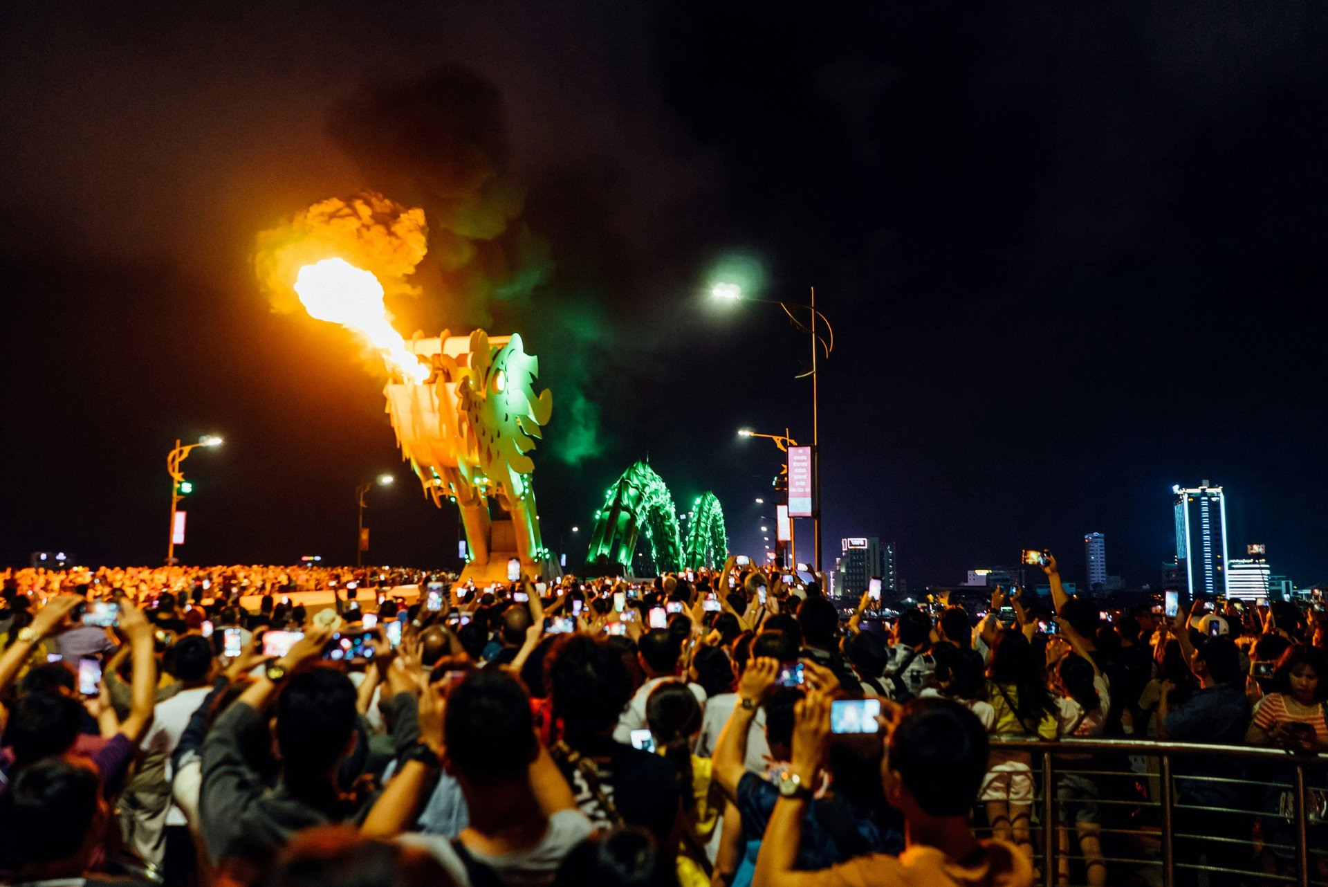 Crowd watching the Dragon Bridge fire show at night in Da Nang