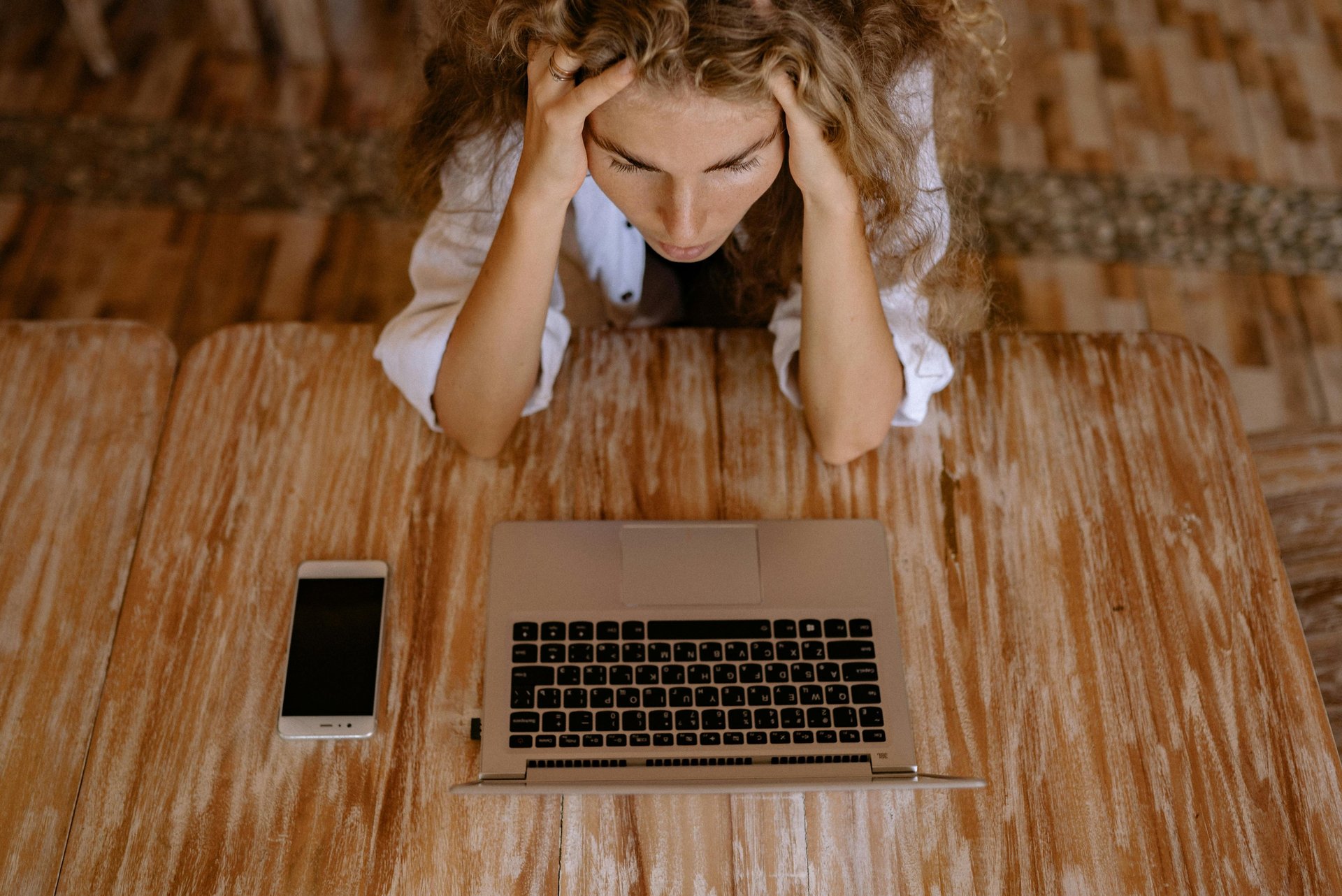 a woman sitting at a table with a laptop and a cell phone