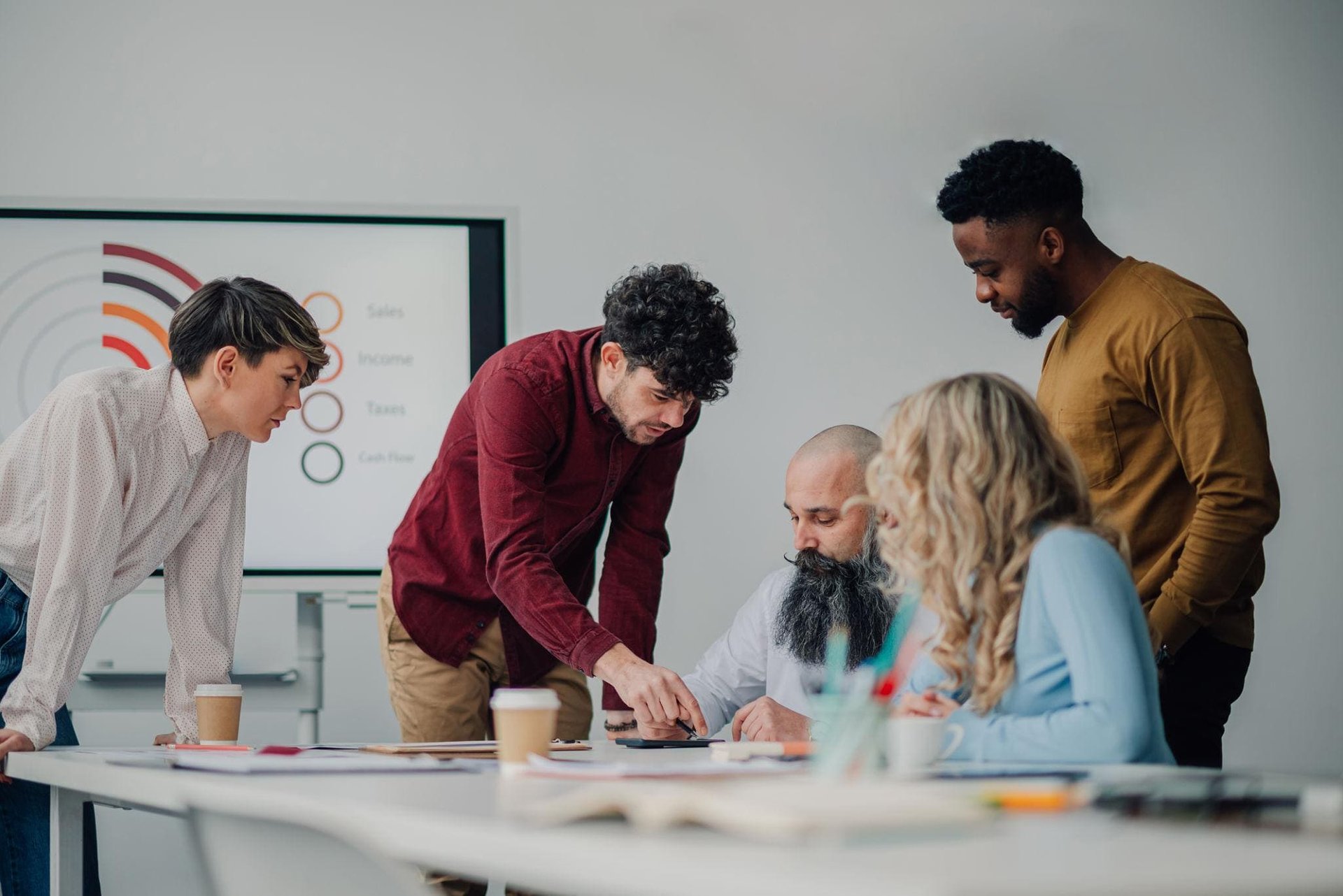 A diverse group of five people engaged in a collaborative meeting around a table