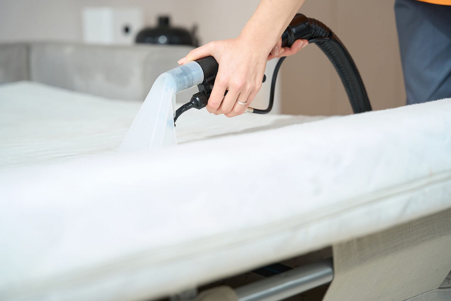 a person is cleaning a mattress with a vacuum