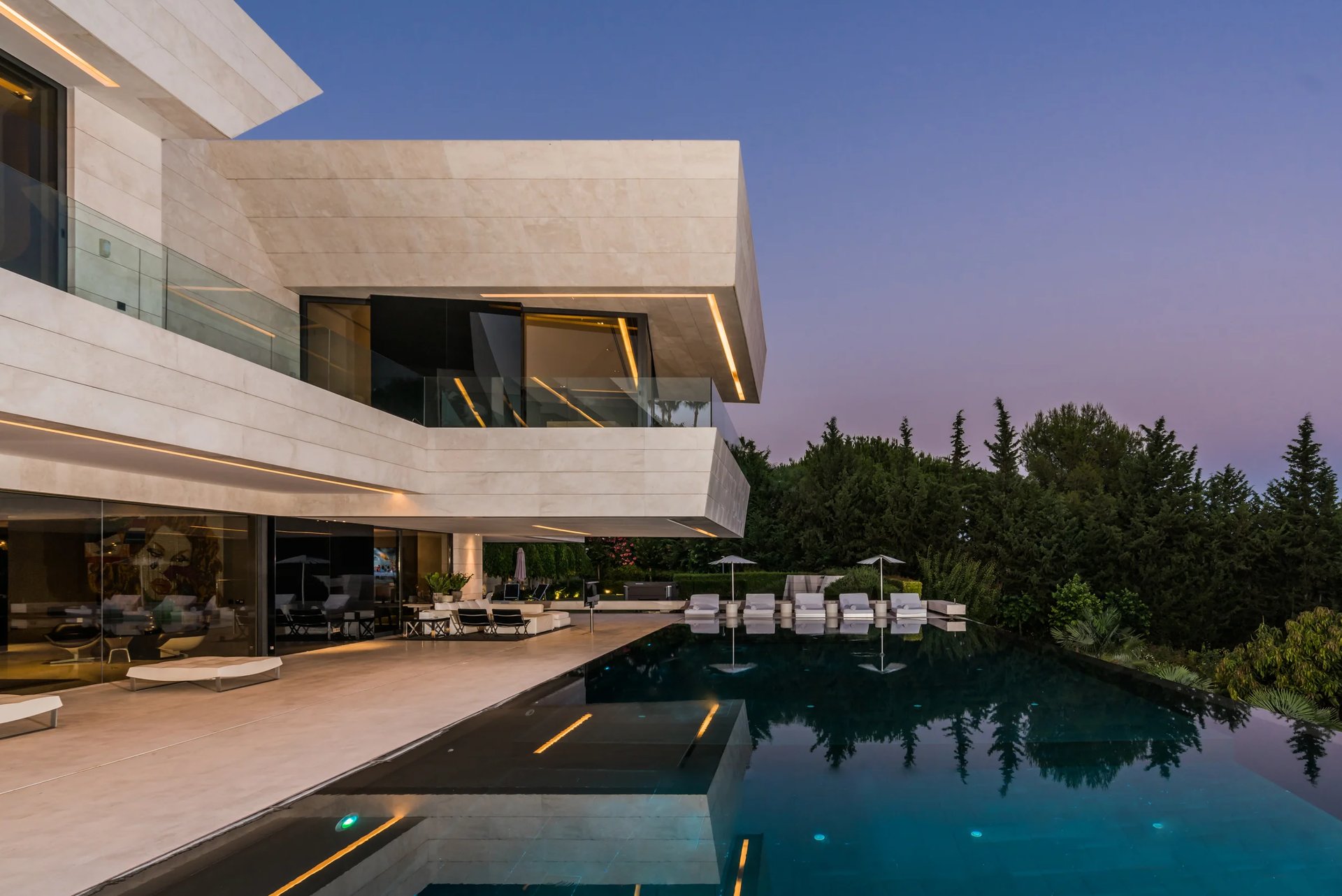 Dusk terrace with illuminated pool and glass façade