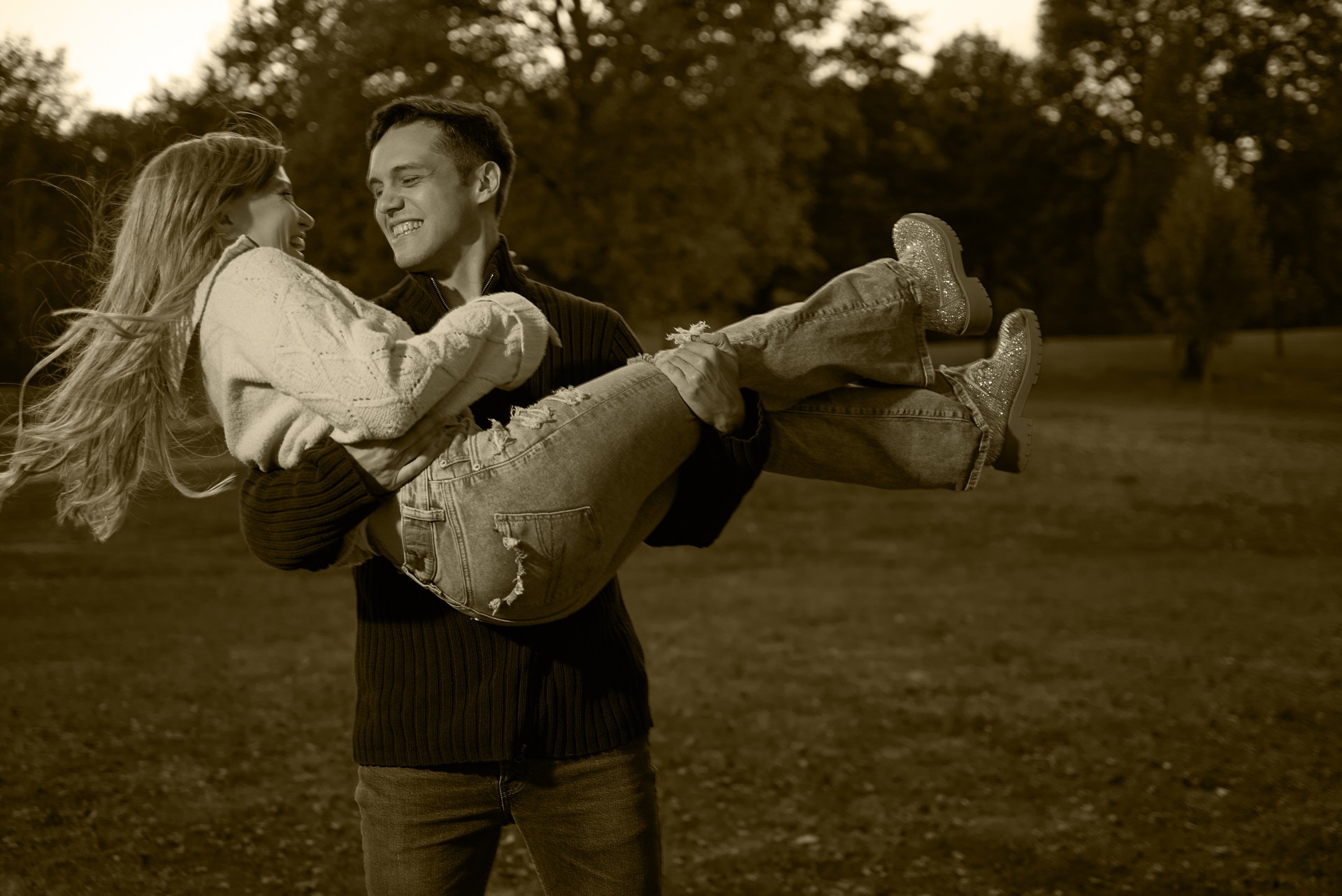a man carrying a woman on his arms in a park