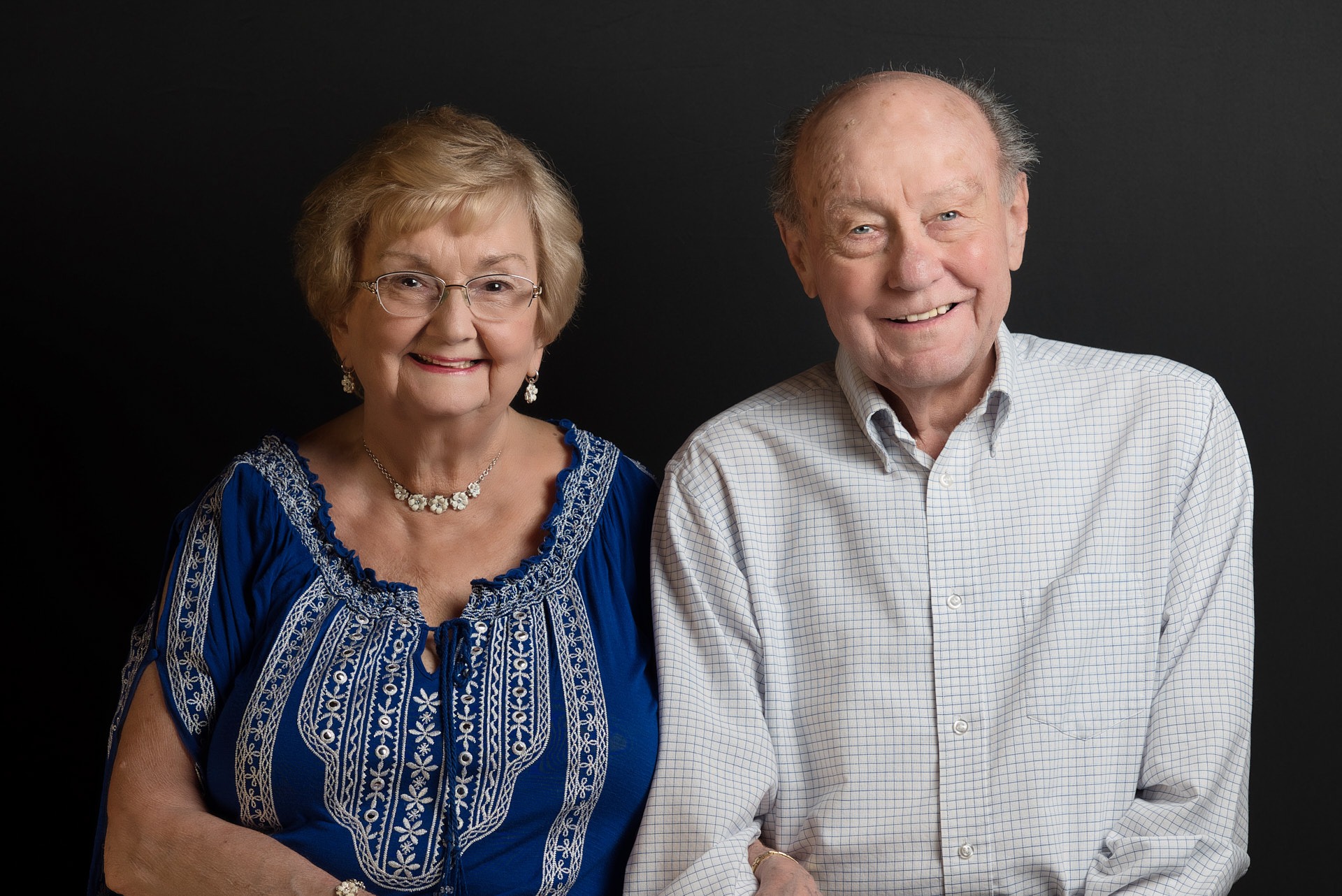 a man and woman sitting next to each other smiling holding hands