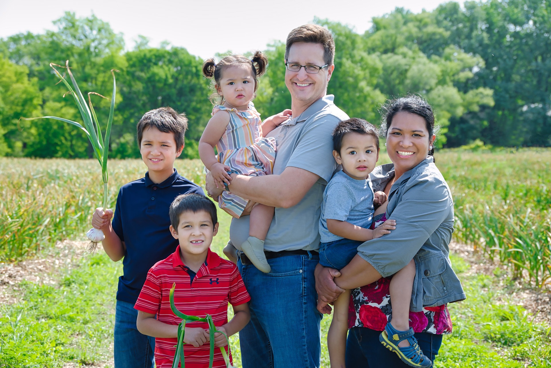 a family of four children posing for a photo in the garlic farm