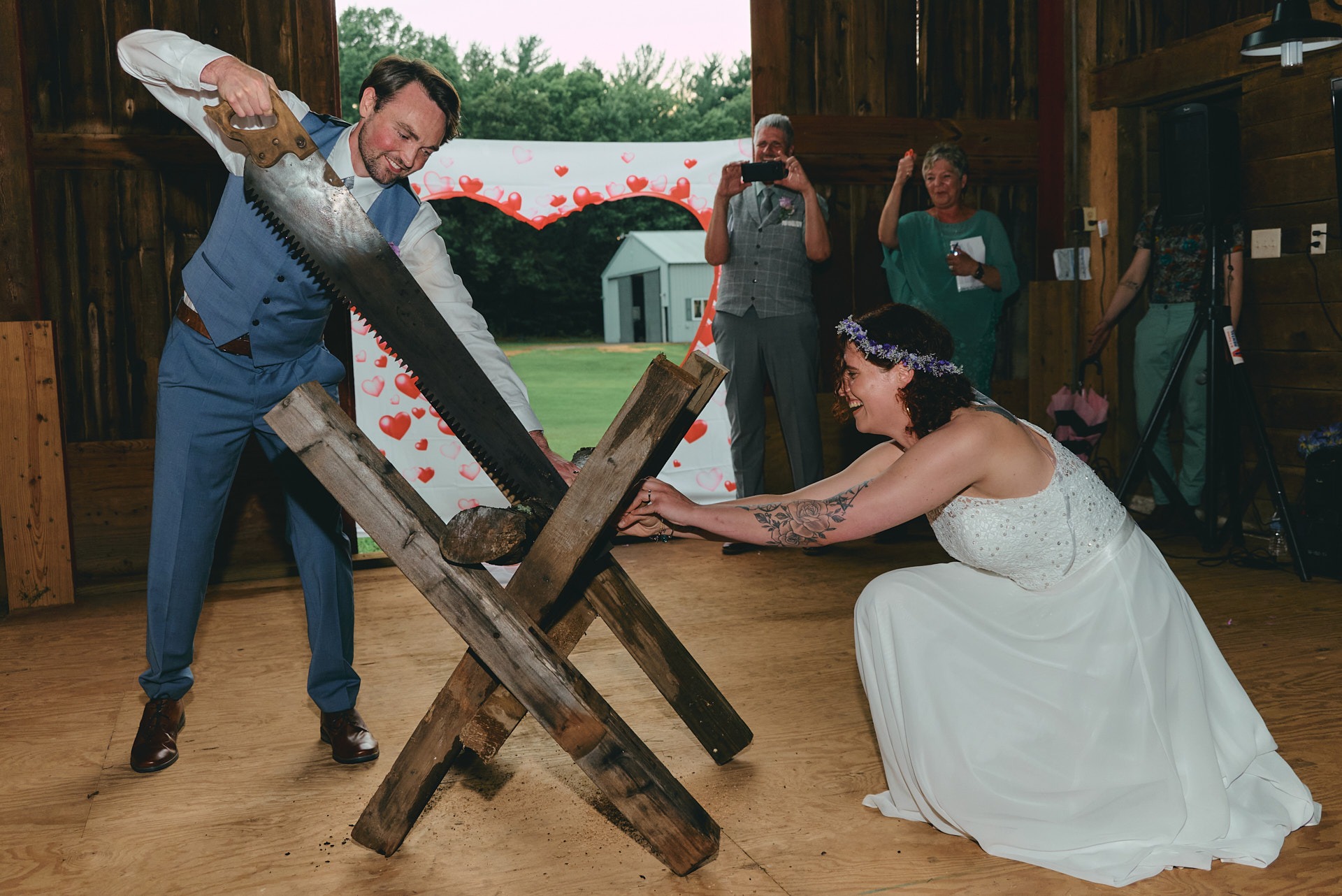 a groom and a bride cutting a piece of wood with a saw together