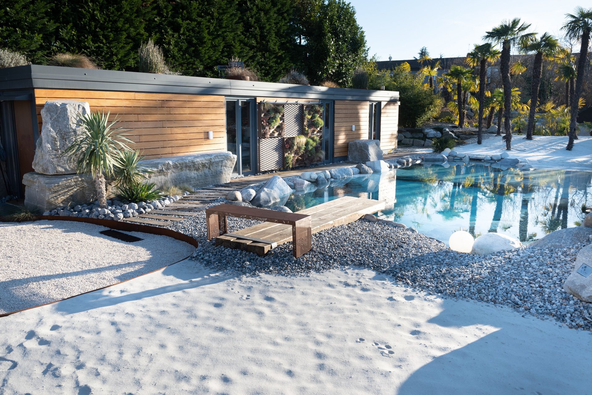 modulo prefabbricato a bordo piscina naturale con rocce e spiaggia bianca