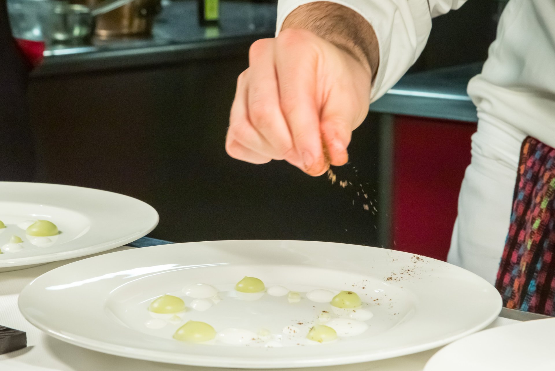 uno chef che condisce il suo piatto