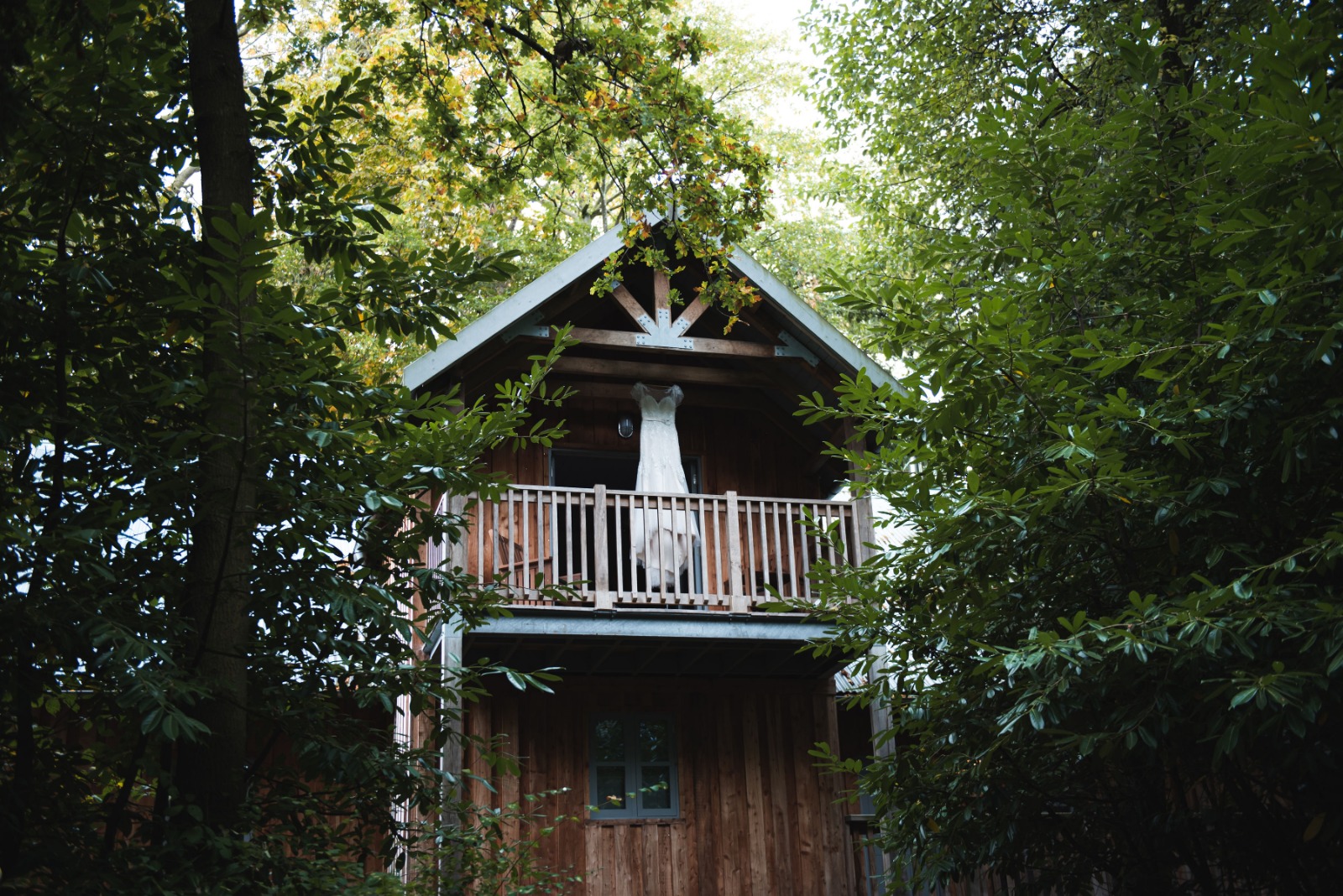 a wedding dress hanging from a lodge treehouse
