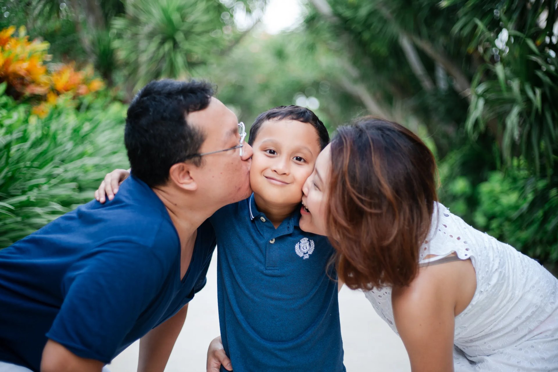 Parents kissing child during family photography session at The Mulia Nusa Dua Bali