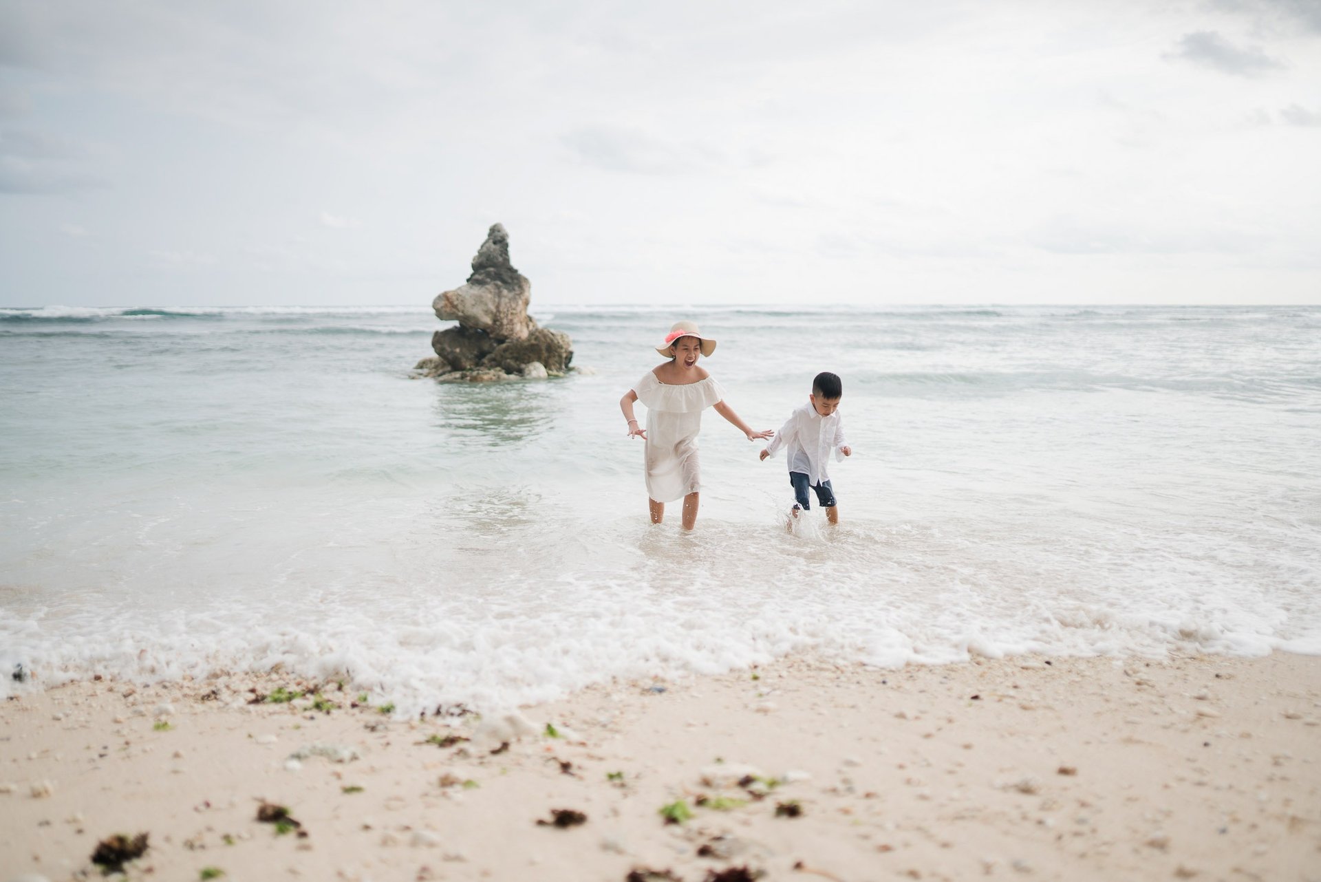 Family walking along the open shoreline of Melasti Beach Bali during a peaceful family photography session