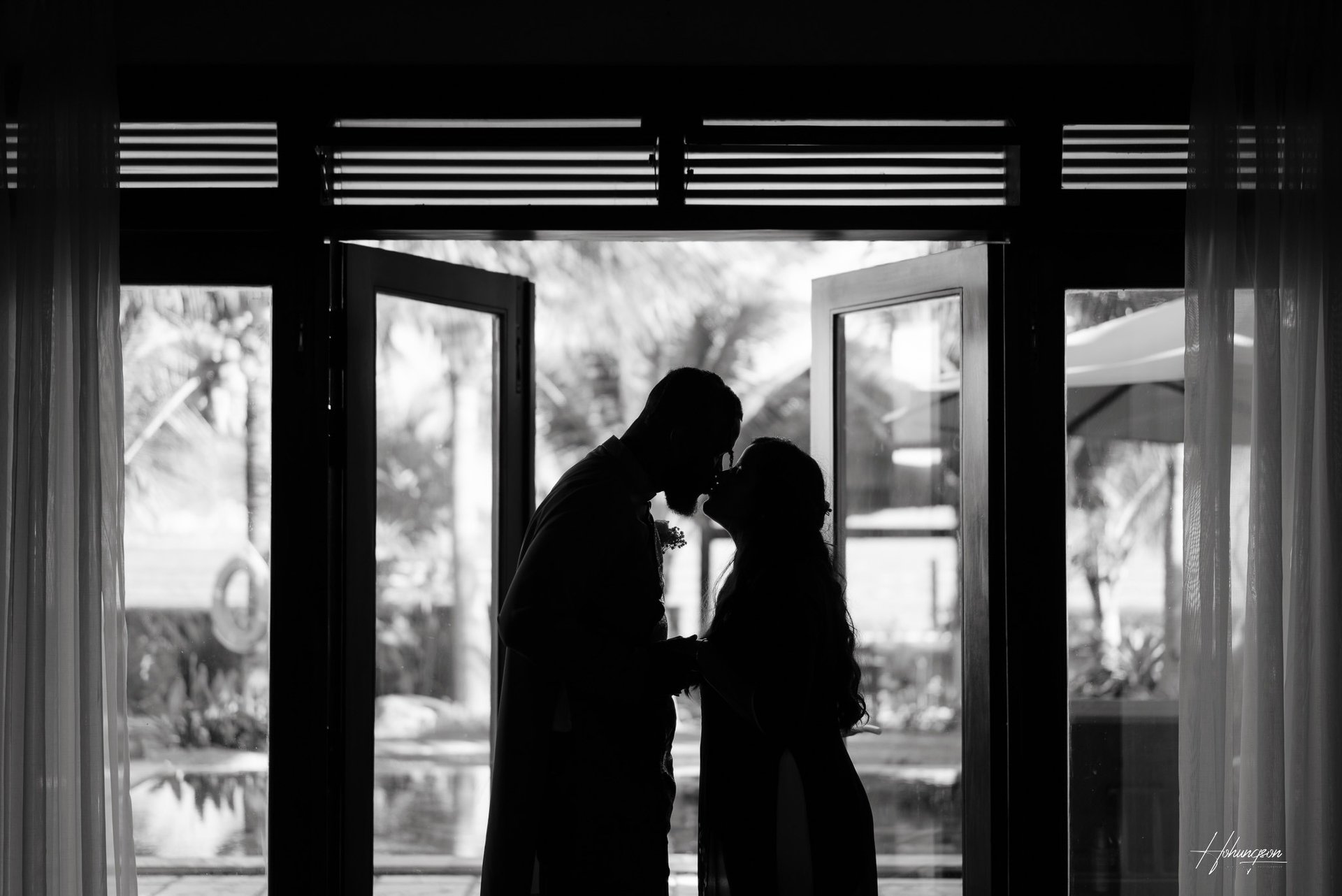 a couple kissing in front of a large window