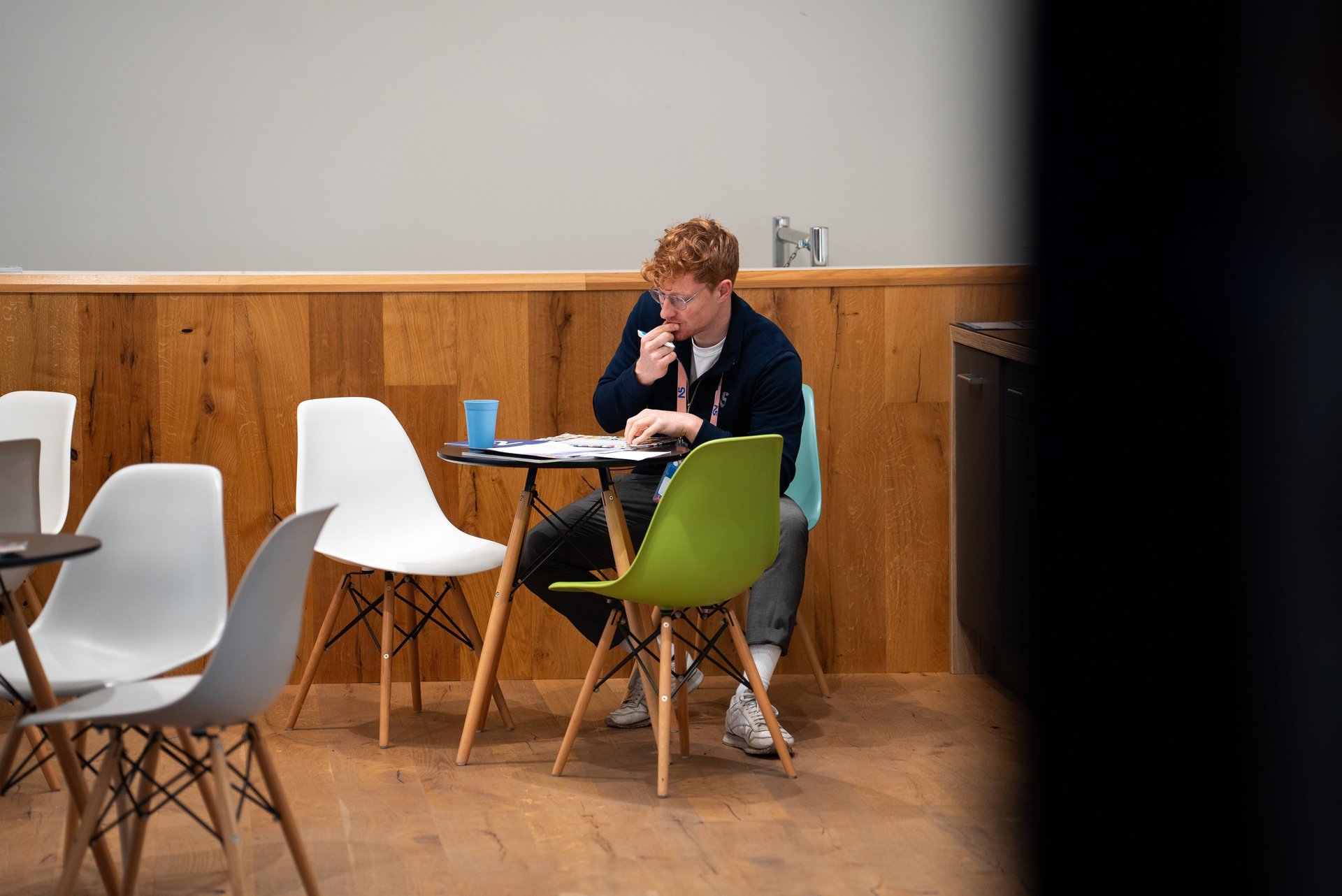 Journalist Przemysław "Przemek" Żuk sitzt an einem Tisch. Er denkt nach und schreibt handschriftliche Notizen.