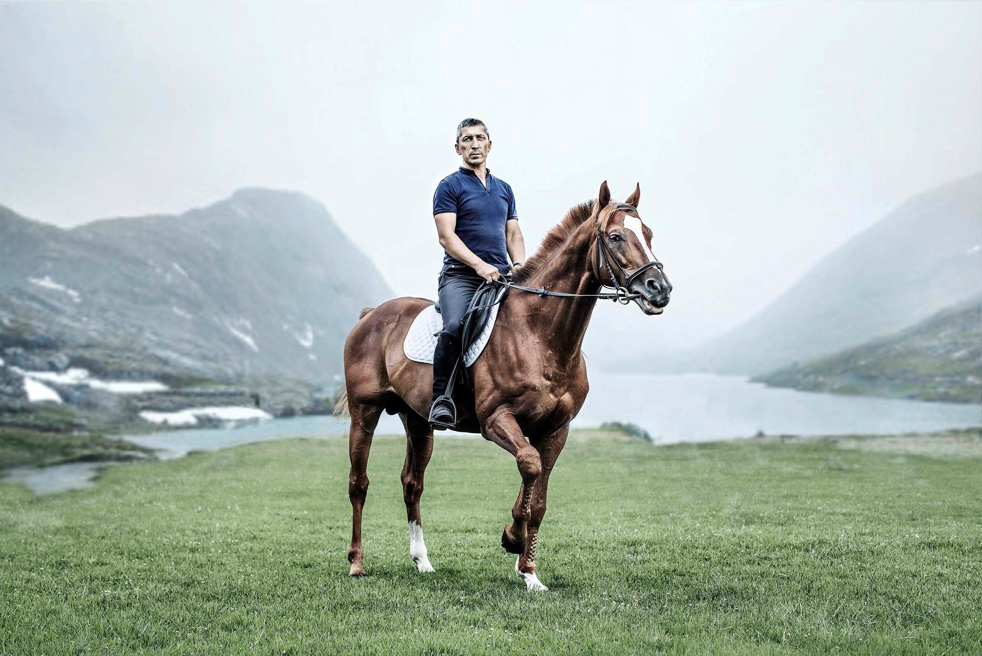 A rider on a horse in a mountain setting, embodying elegance and adventure for an equestrian brand.