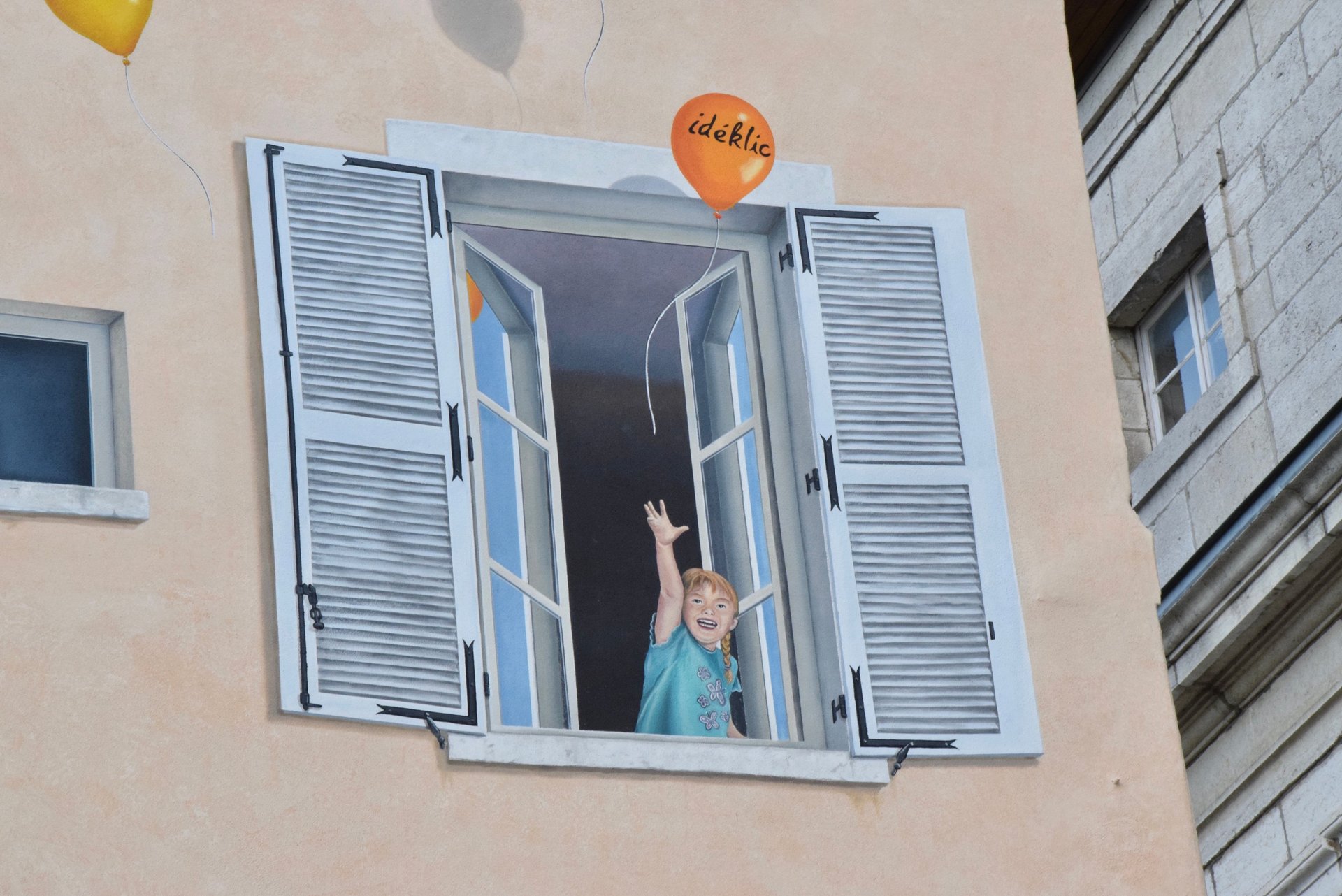 Détail d'un trompe-l'oeil sur façade à Moirans-en-Montagne: Une fillette à une fenêtre au 1er étage.