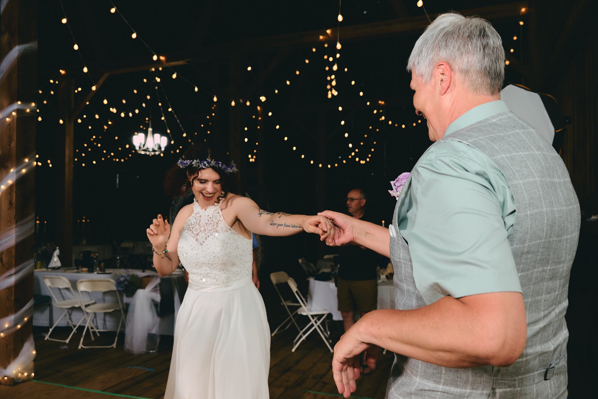 a bride and her father dancing at a wedding and having fun in a barn
