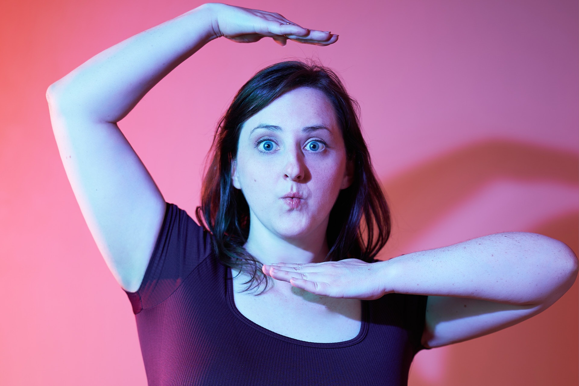 a woman with a fun expression and posture with pink background