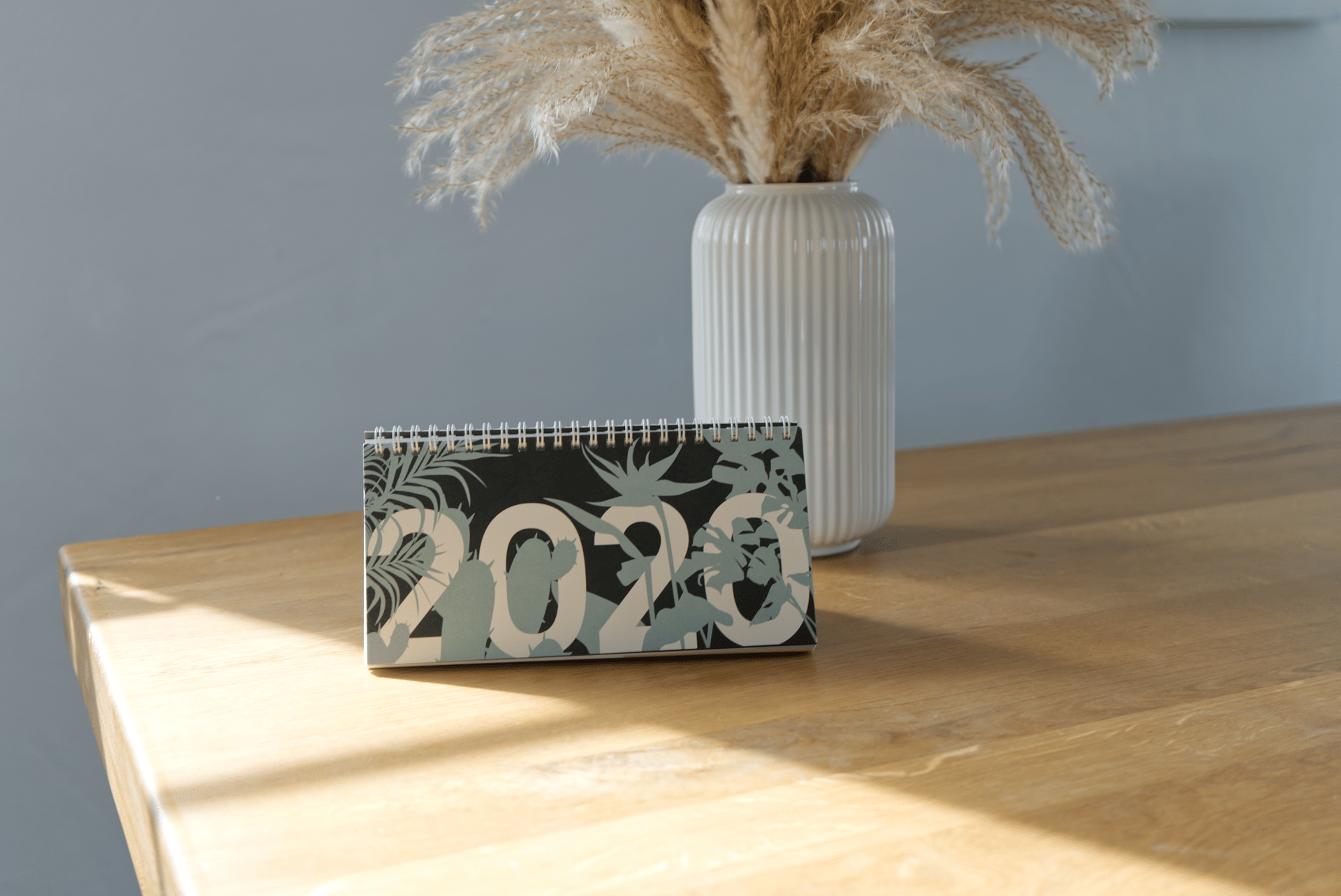 Ein Tischkalender für das Jahr 2020 mit botanischen Motiven auf einem Holztisch.
