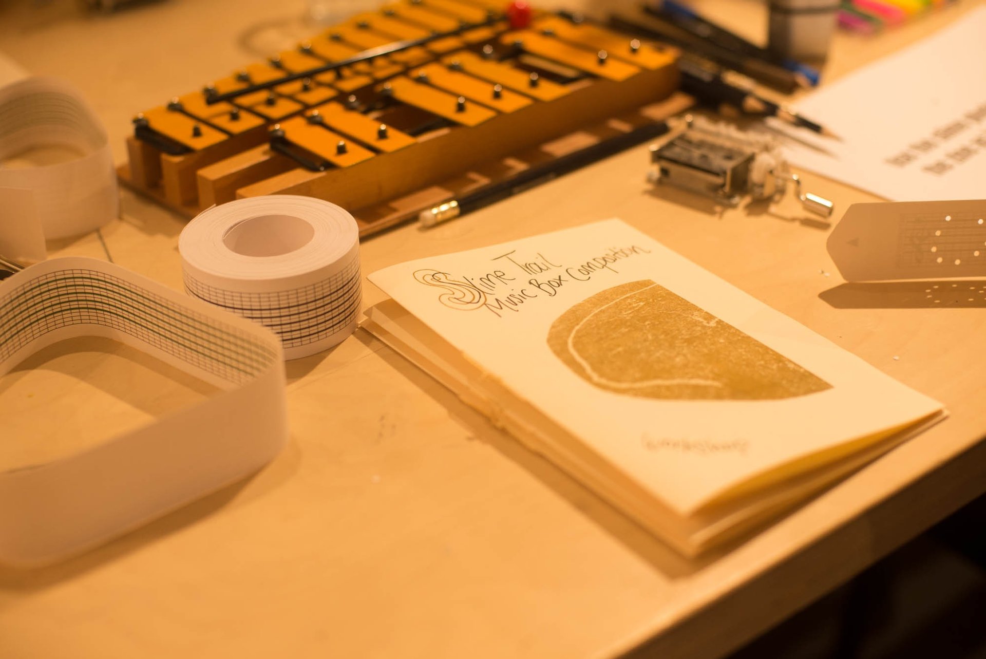 a table with a glockenspiel and a zine about music box composition