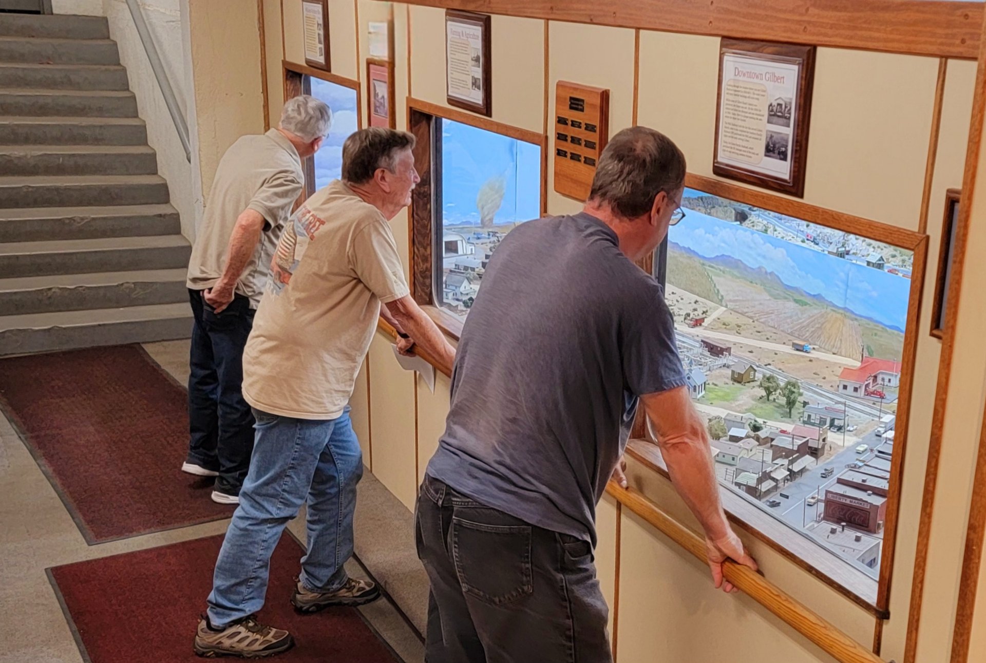Viewing gallery windows with vistors looking at the model train layout